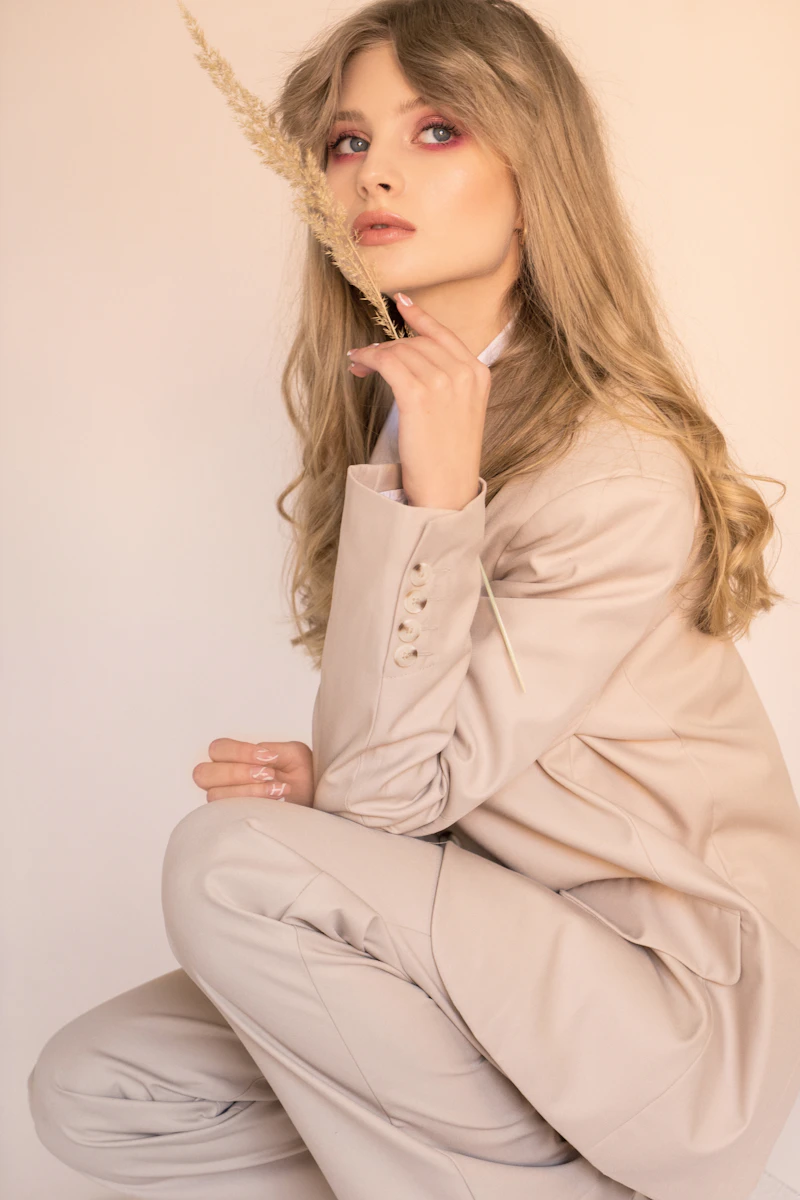 A woman in a soft beige suit holding dried grasses