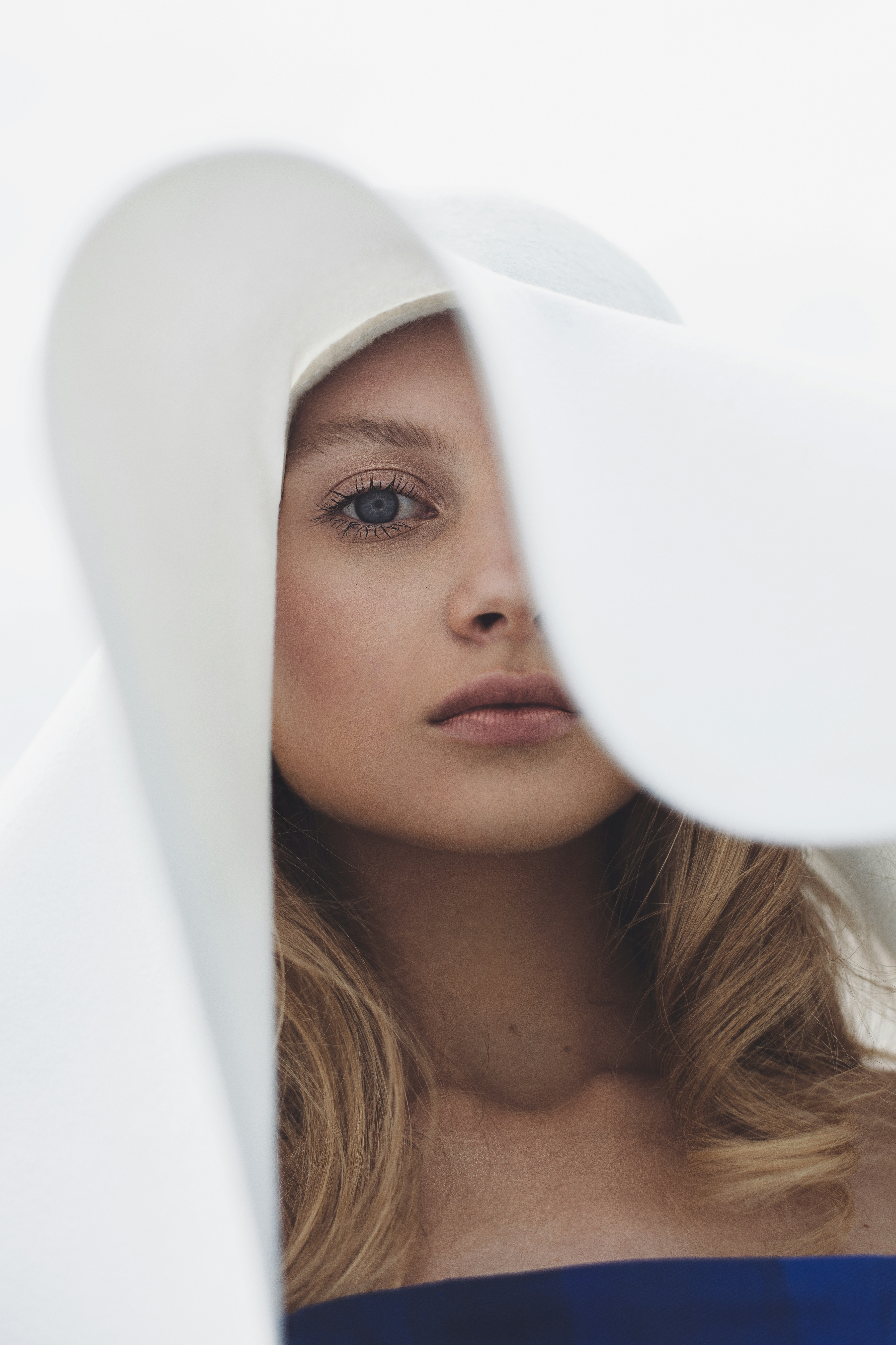 Young woman with blonde hair wearing a large white hat.