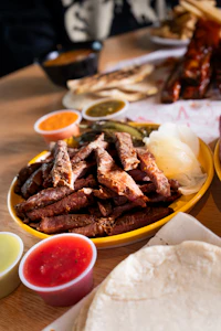 Sliced carne asada with grilled onion, salsas and tortillas