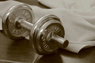 Chrome dumbbell and towel on dark wood