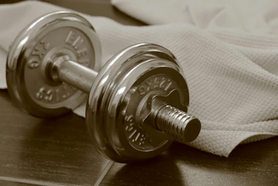 Chrome dumbbell and towel on dark wood.