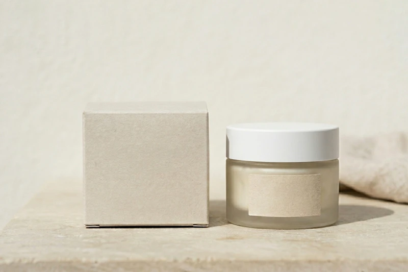 Frosted cream jar beside a plain kraft box