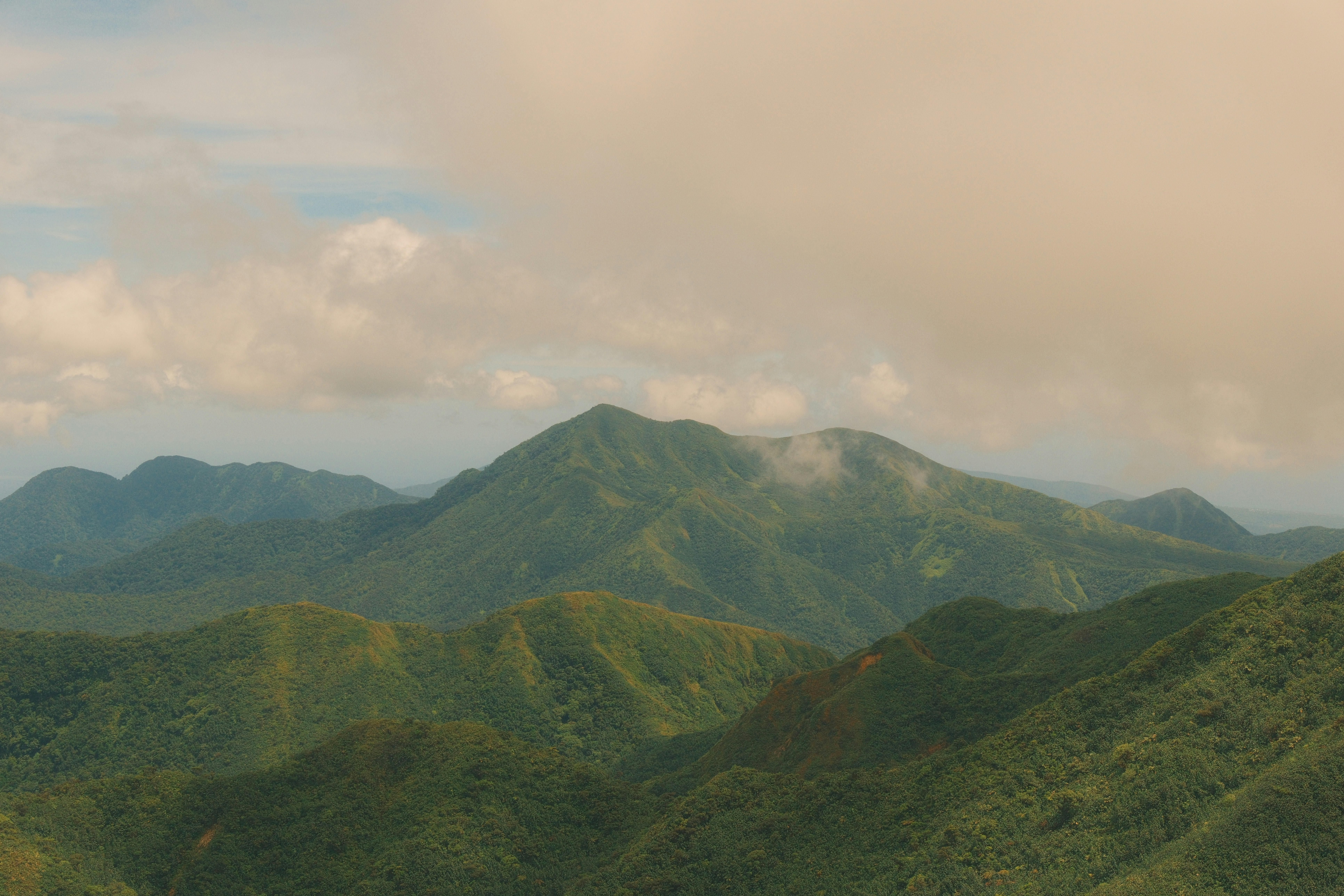 Lush green mountains under a cloudy sky.