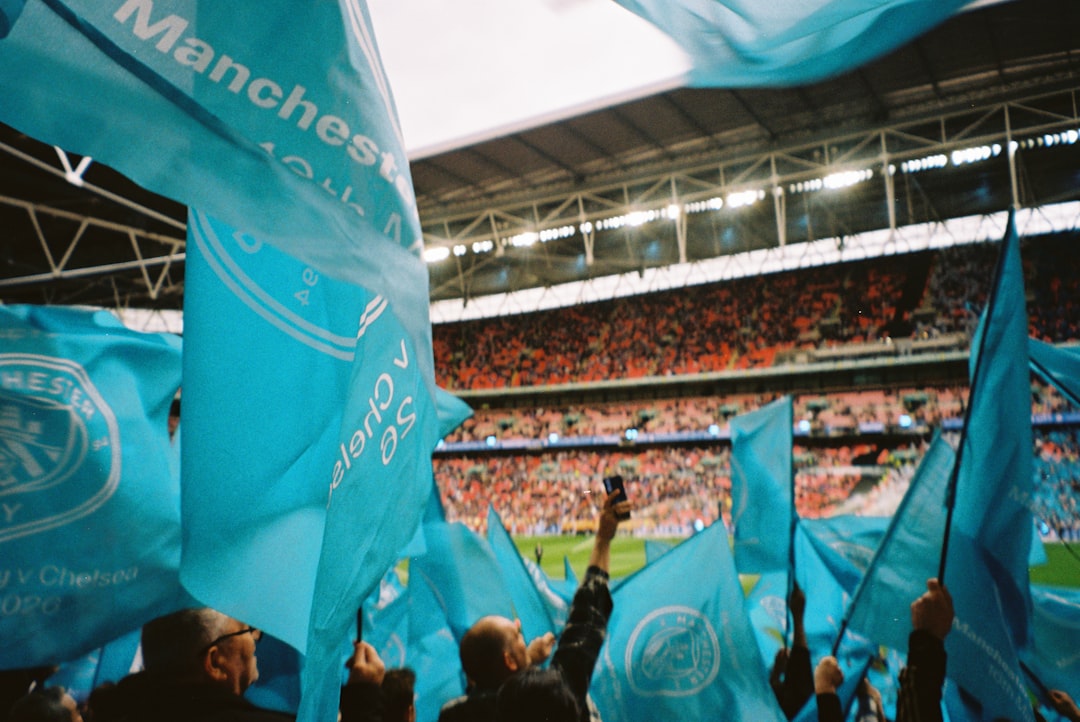 Fans waving light blue flags in a crowded stadium.
