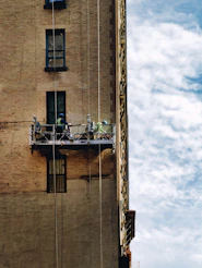 Workers on a suspended scaffold repairing a building facade.