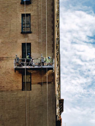 Workers on a suspended scaffold repairing a building facade.