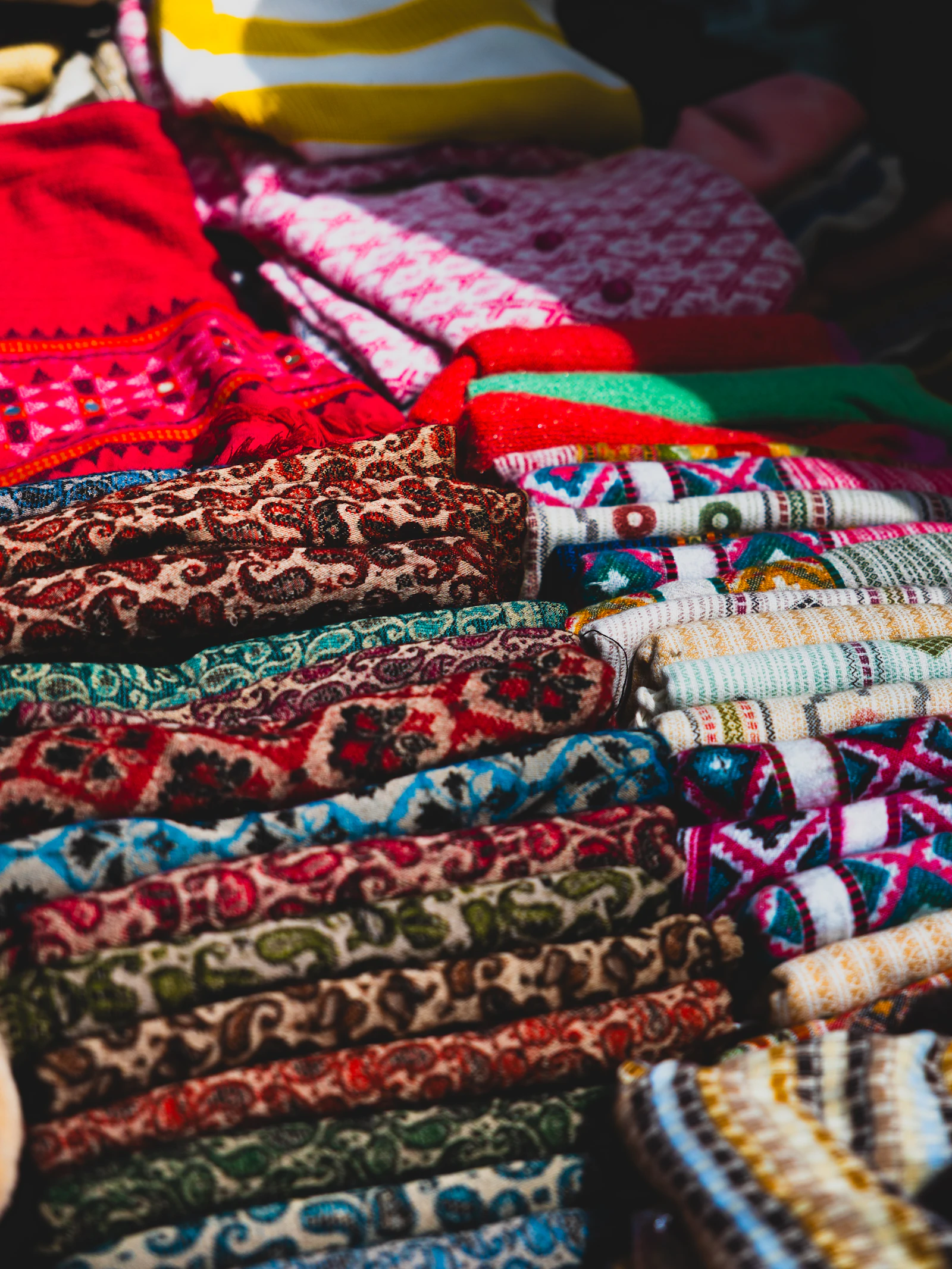 Patterned shawls and fabric stacked for sale in a shop