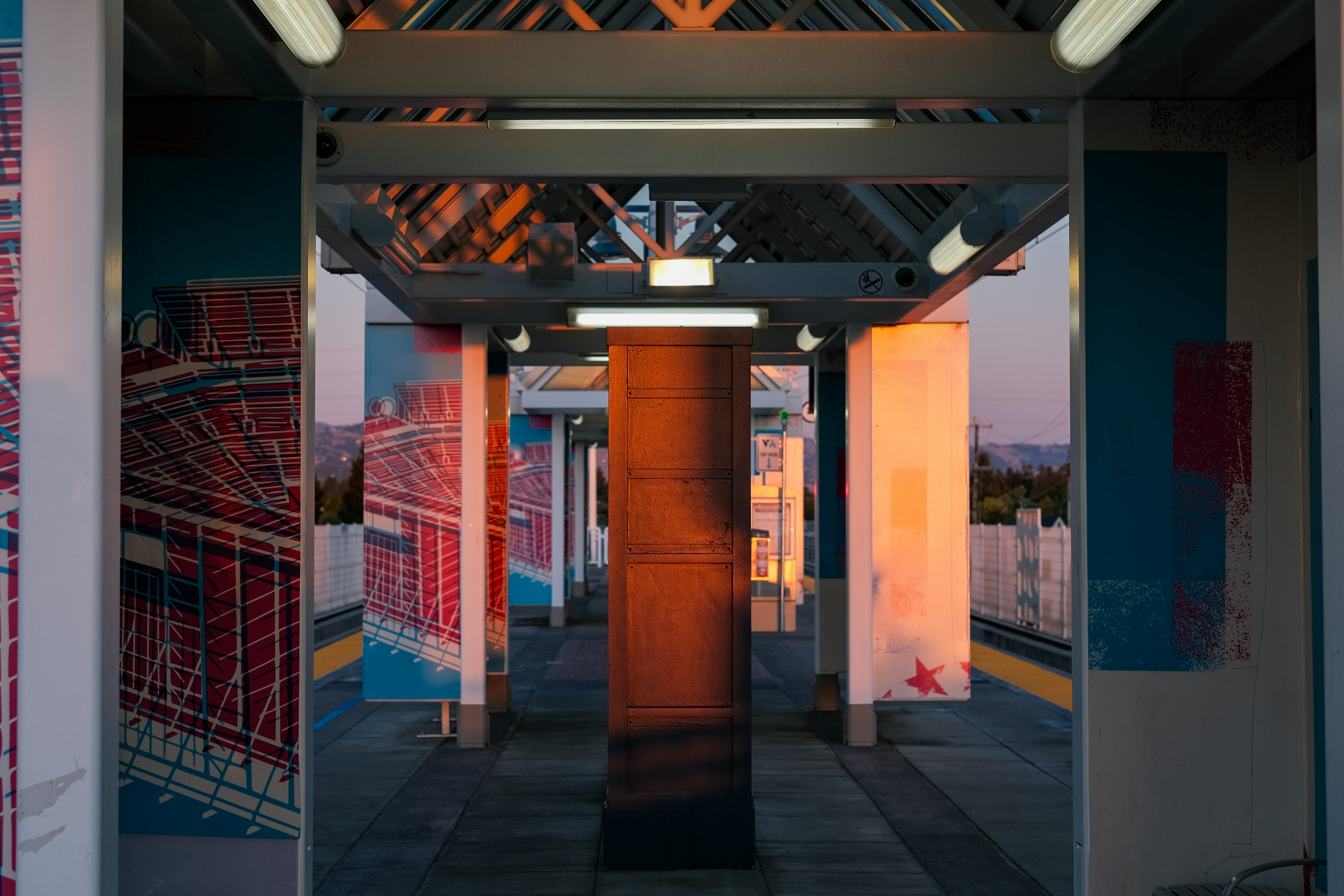 A train station platform bathed in warm sunset light.