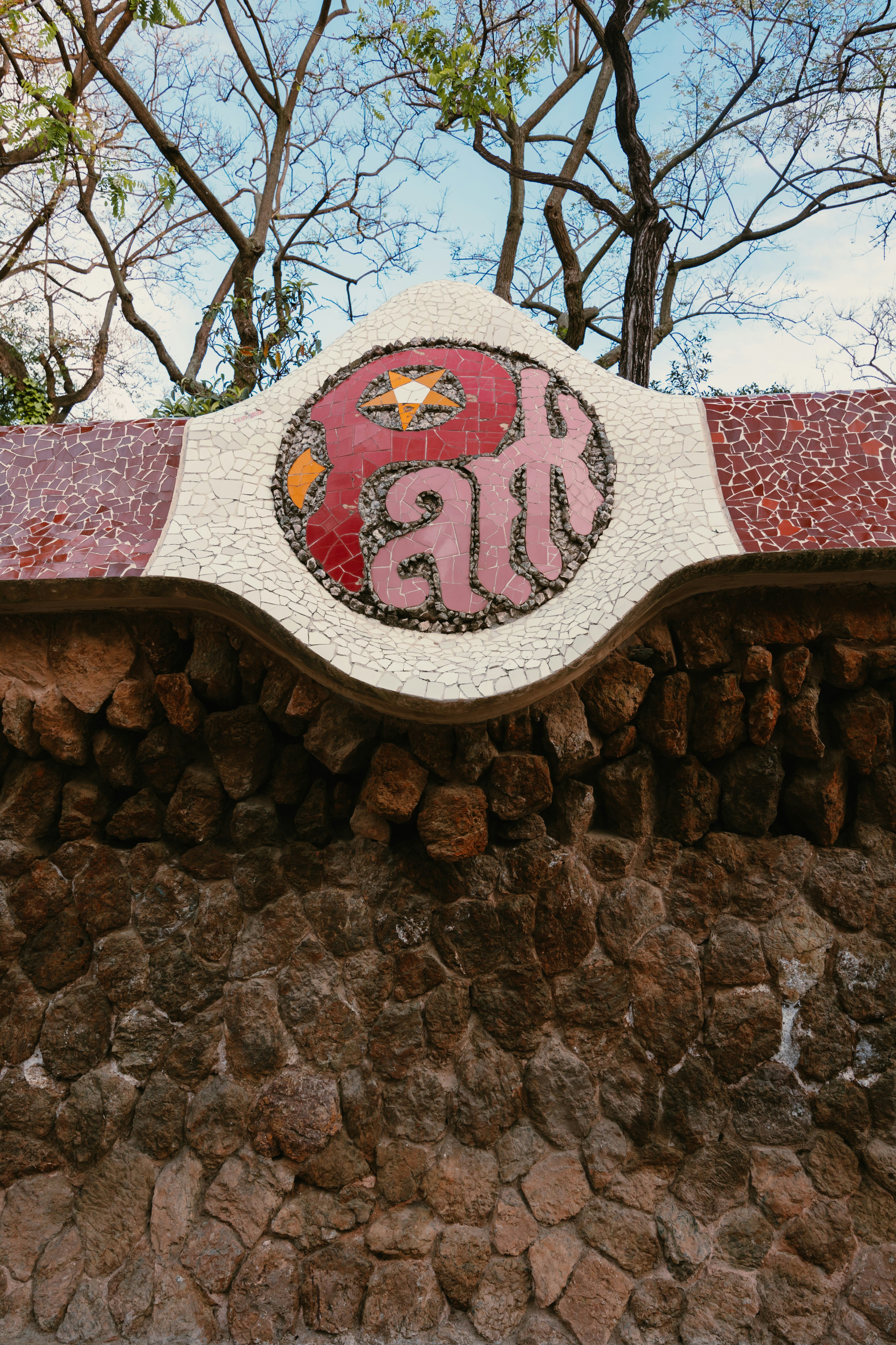 Mosaico stilizzato del 'parco' su un muro di pietra.