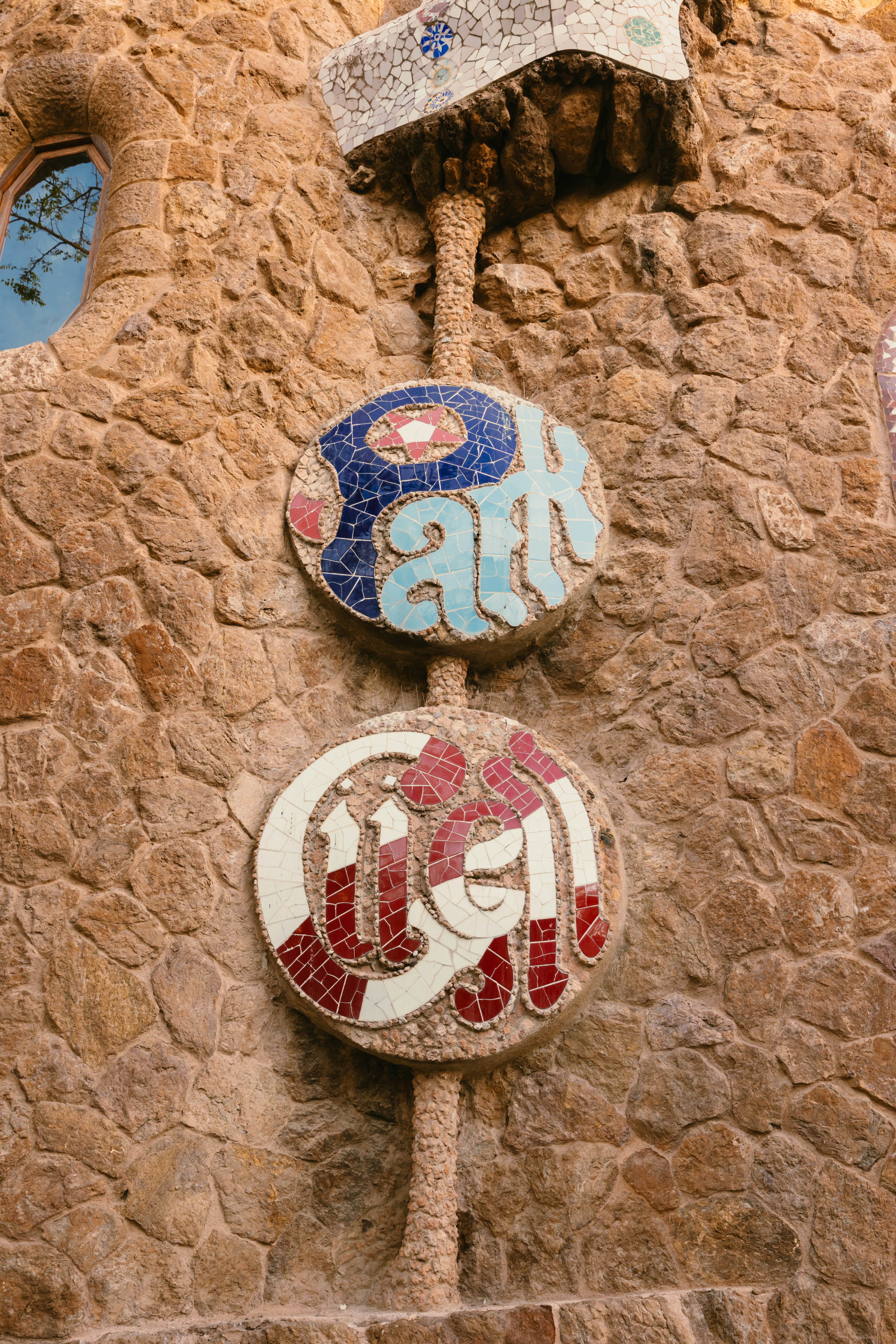 Medaglioni colorati a mosaico adornano un muro di pietra rustica.