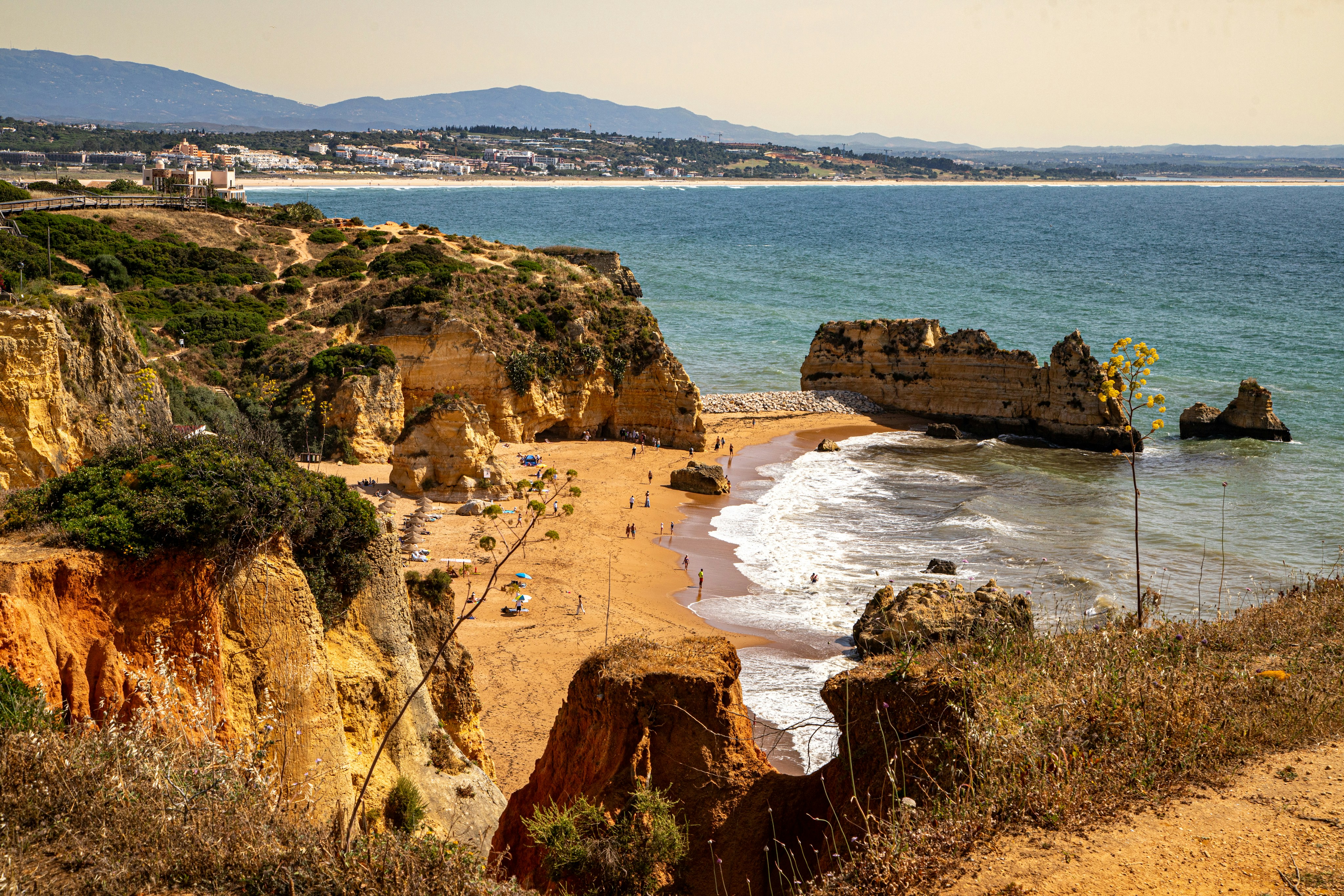 Golden cliffs overlook a sandy beach and blue ocean.