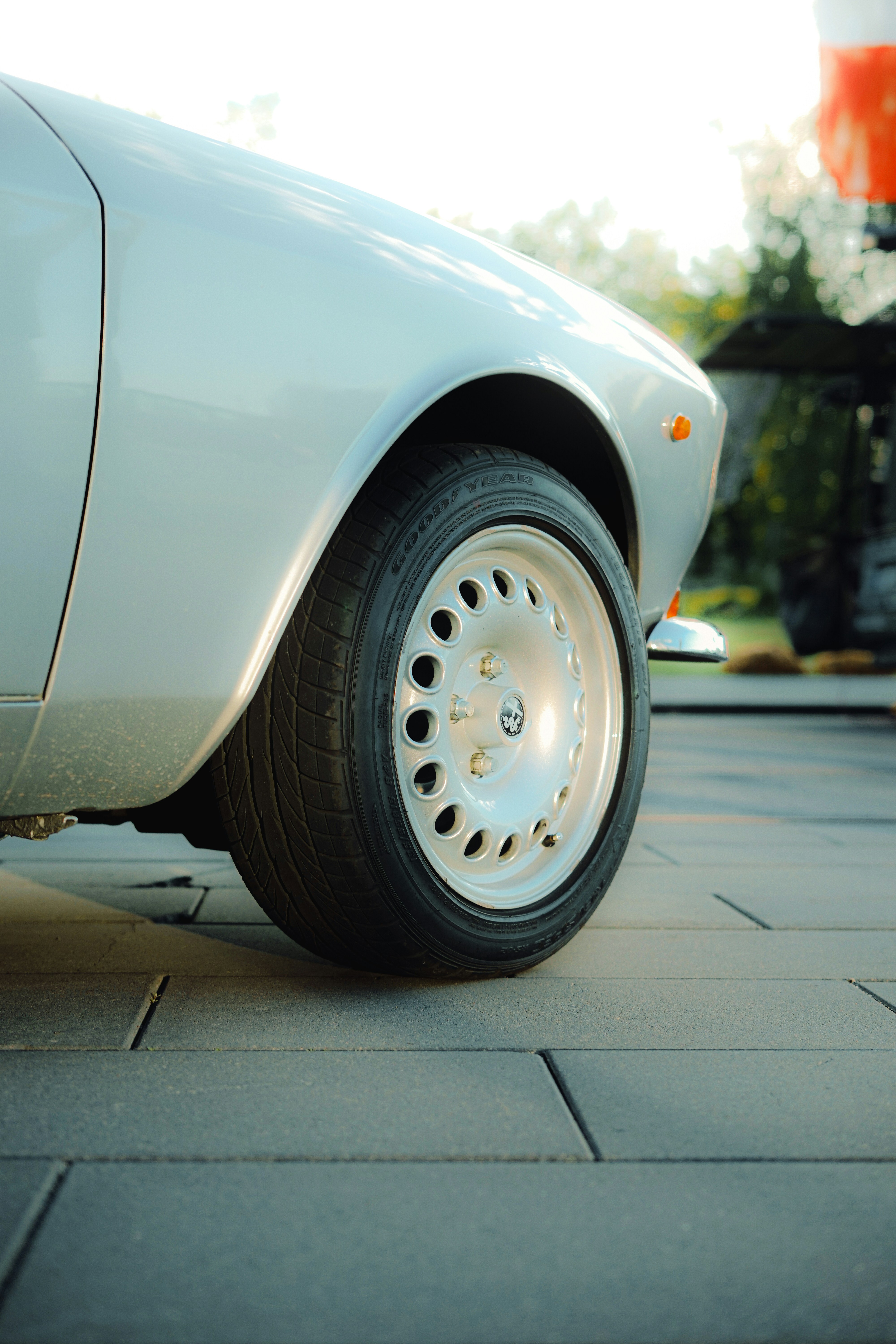 Front wheel and fender of a classic silver car.