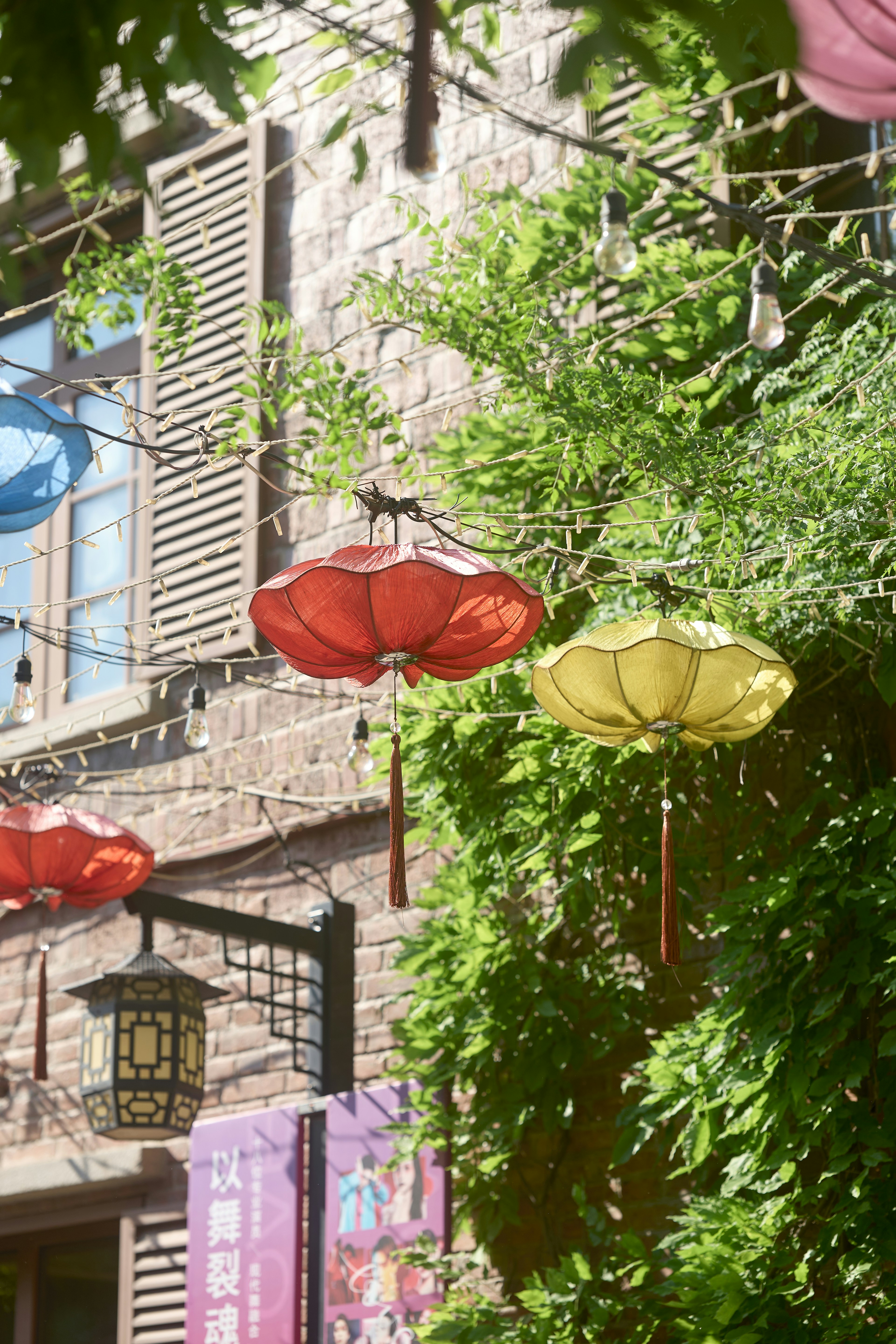 Lanternas tradicionais vermelhas e amarelas iluminam um prédio de tijolos.