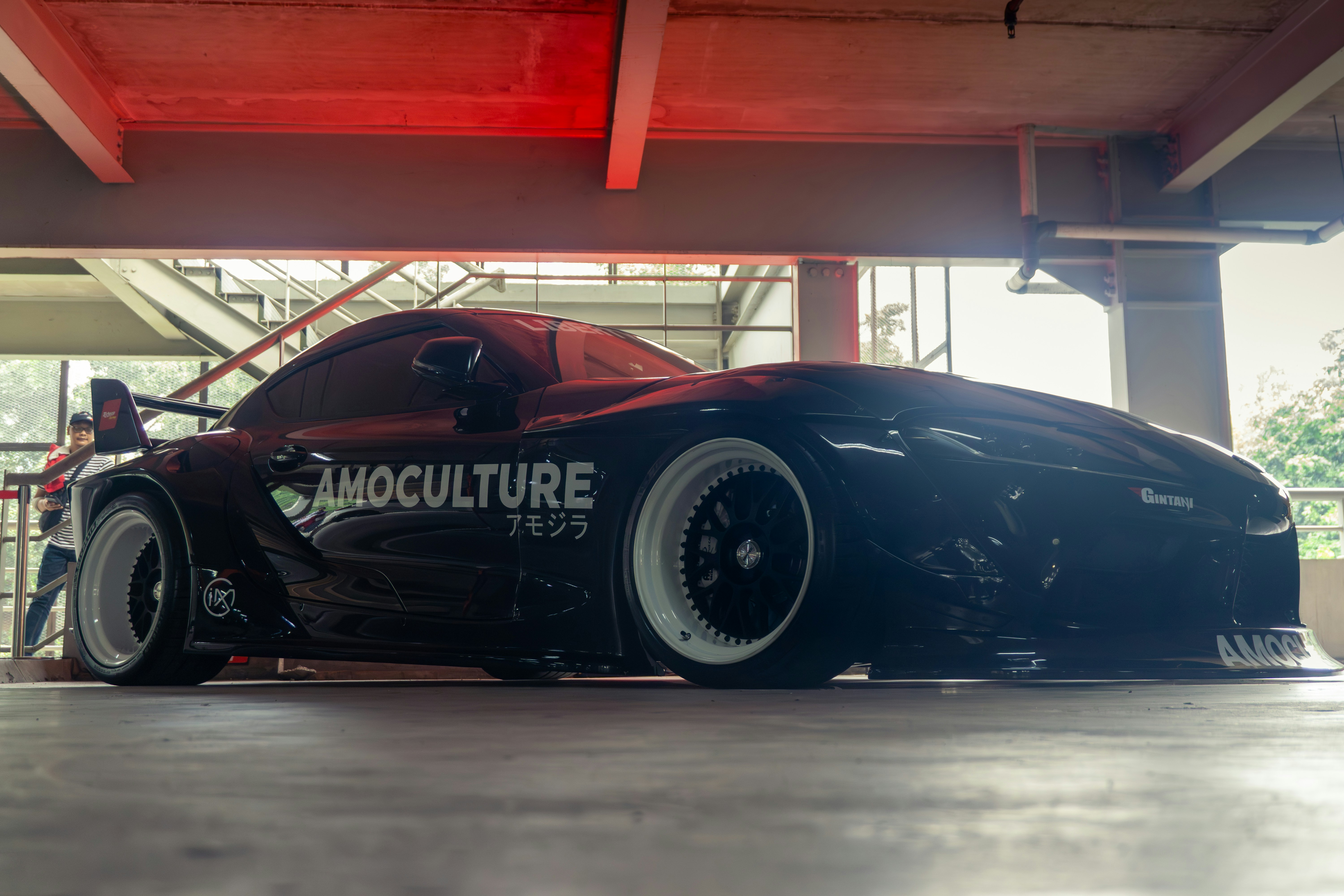 Una sportiva nera personalizzata con ruote bianche parcheggiata all'interno