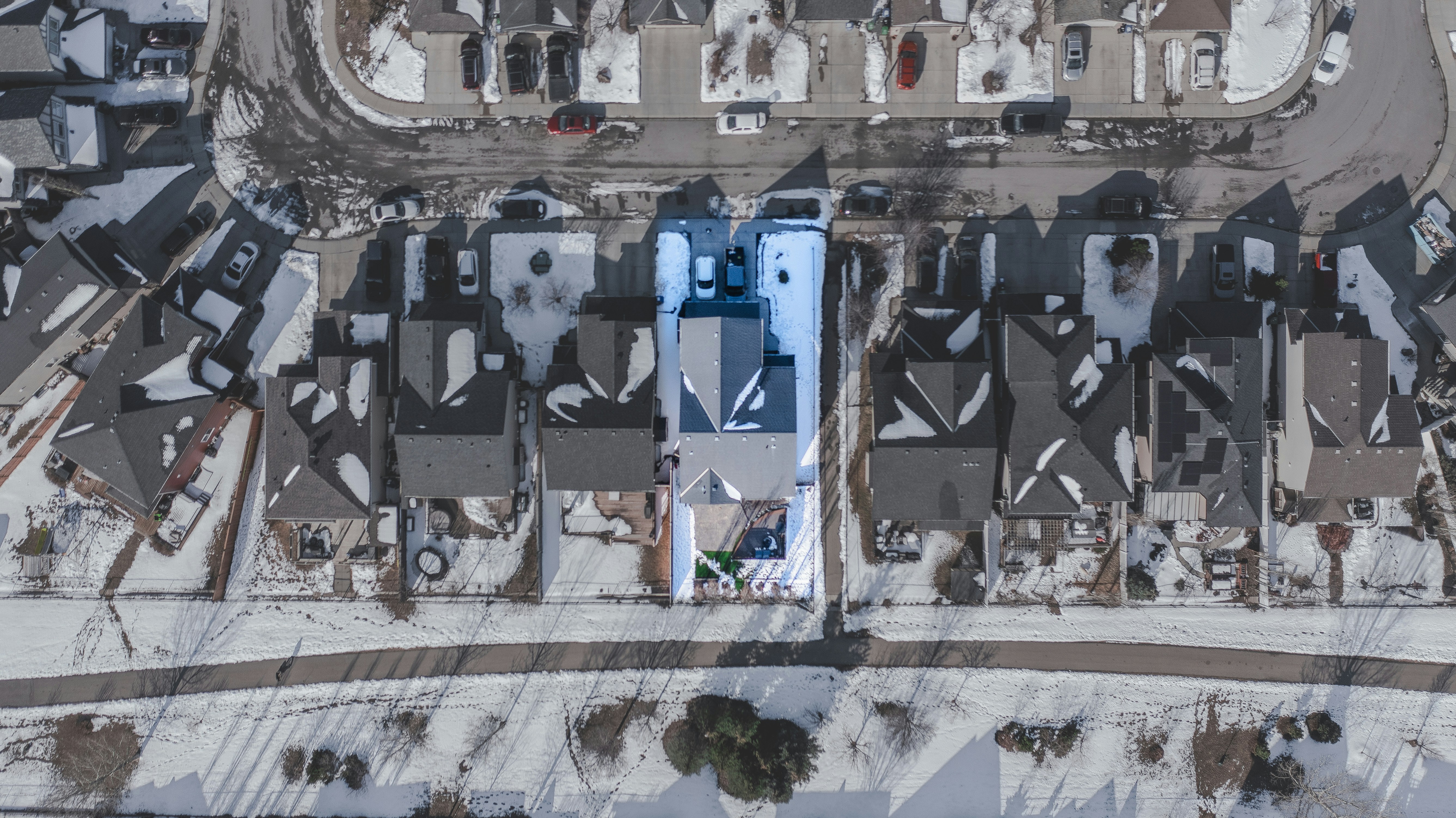 Aerial view of snow-covered residential neighborhood with one house highlighted.