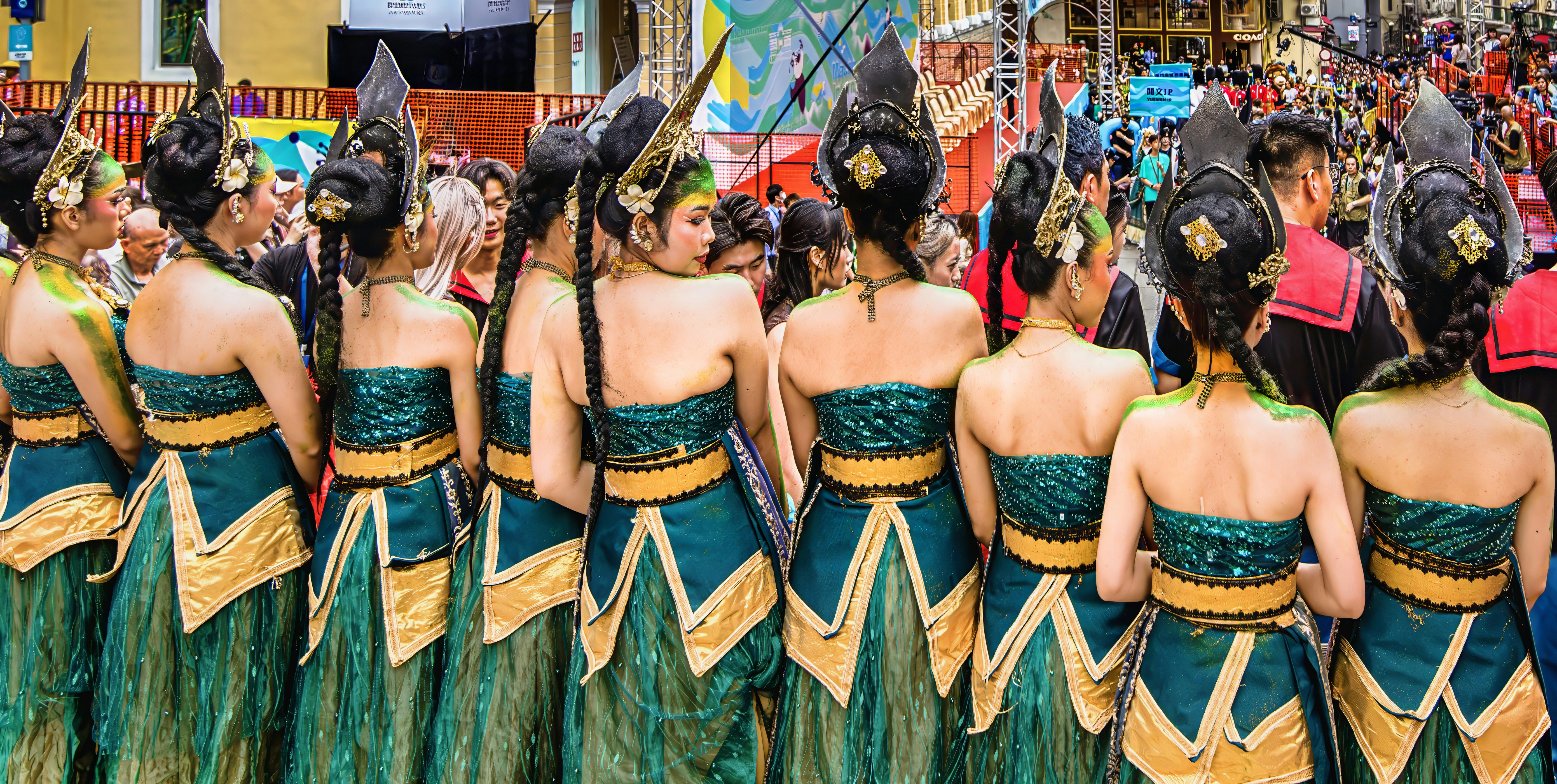 Wanita dengan kostum tradisional hijau dan emas dari belakang.