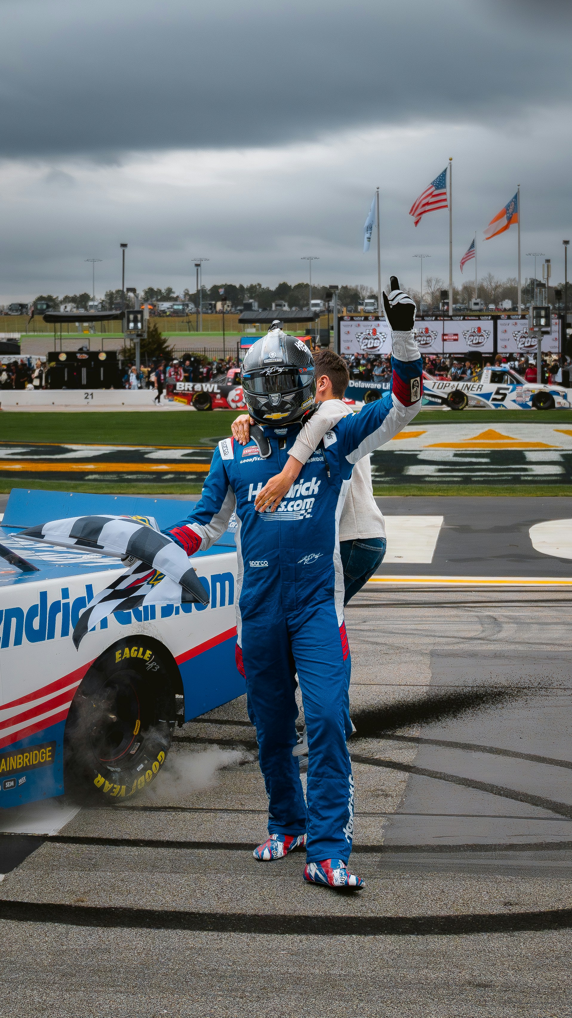 Un pilote de course célèbre la victoire sur la piste avec des pneus fumants.
