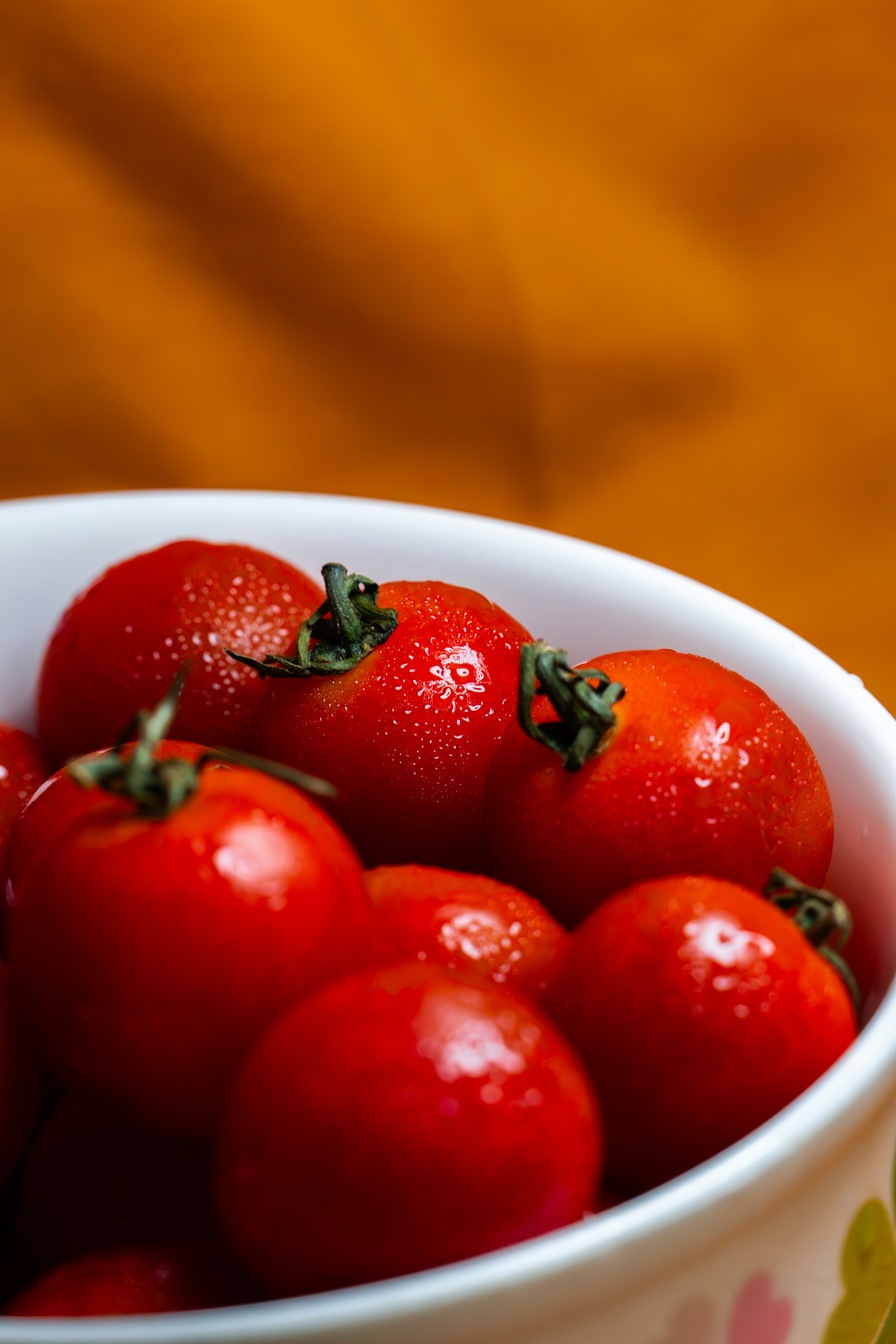 A bowl of fresh red cherry tomatoes with water droplets.