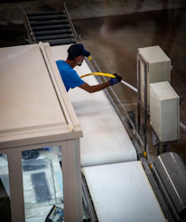 Industrial worker spraying a dusty conveyor belt system
