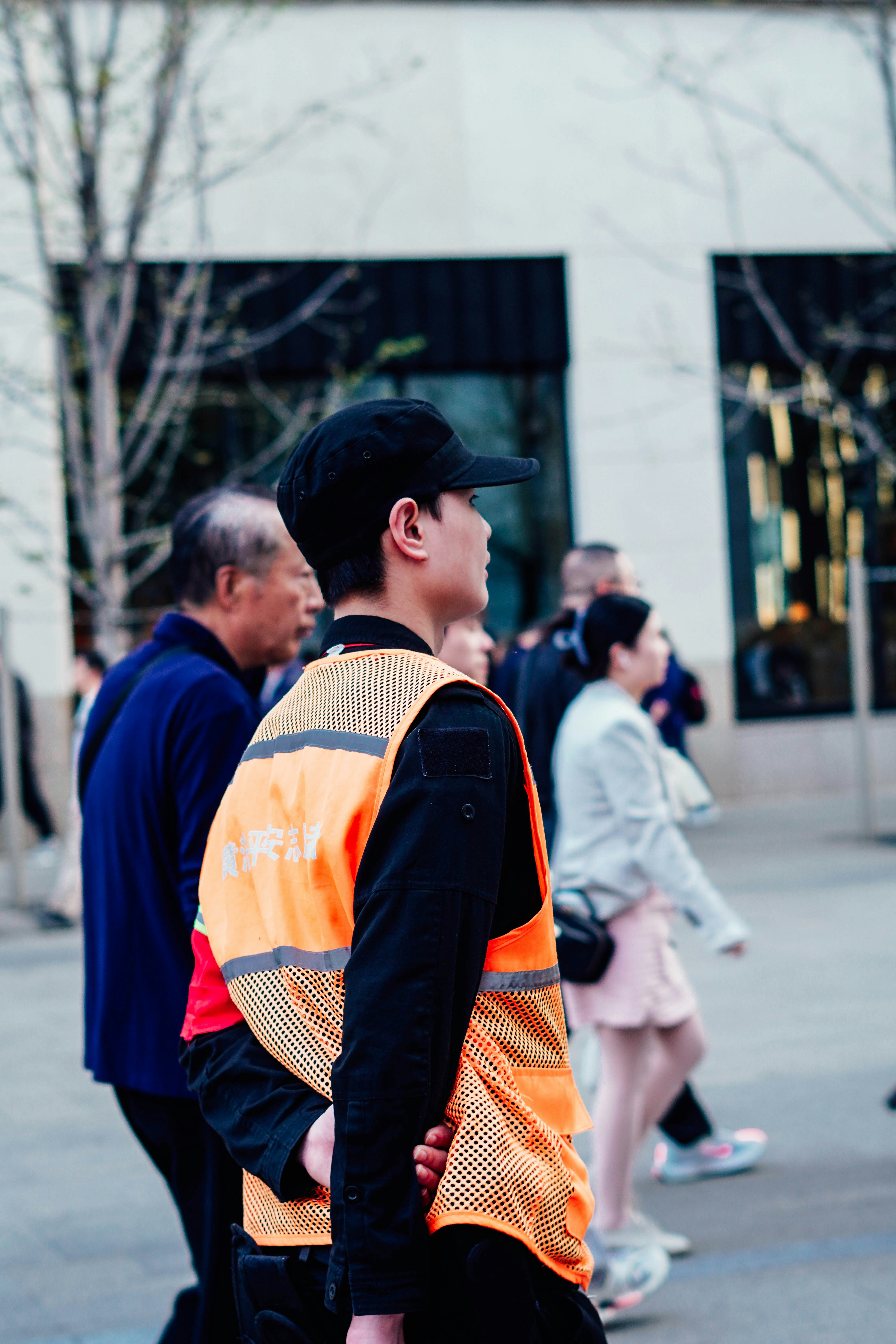 Persona que lleva un chaleco reflectante naranja de pie en una calle.