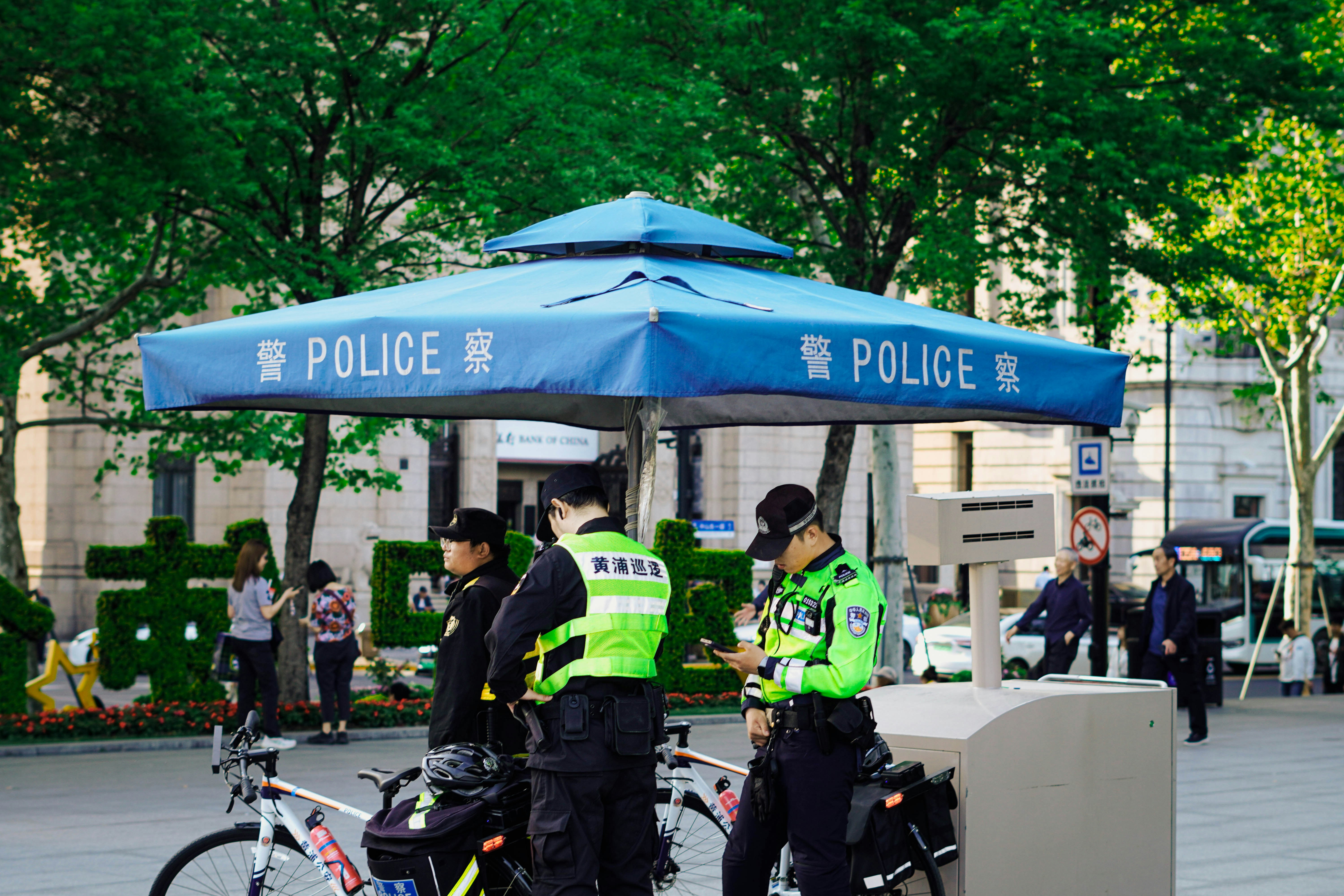 Policiais em pé ao lado de uma cabine azul com bicicletas.