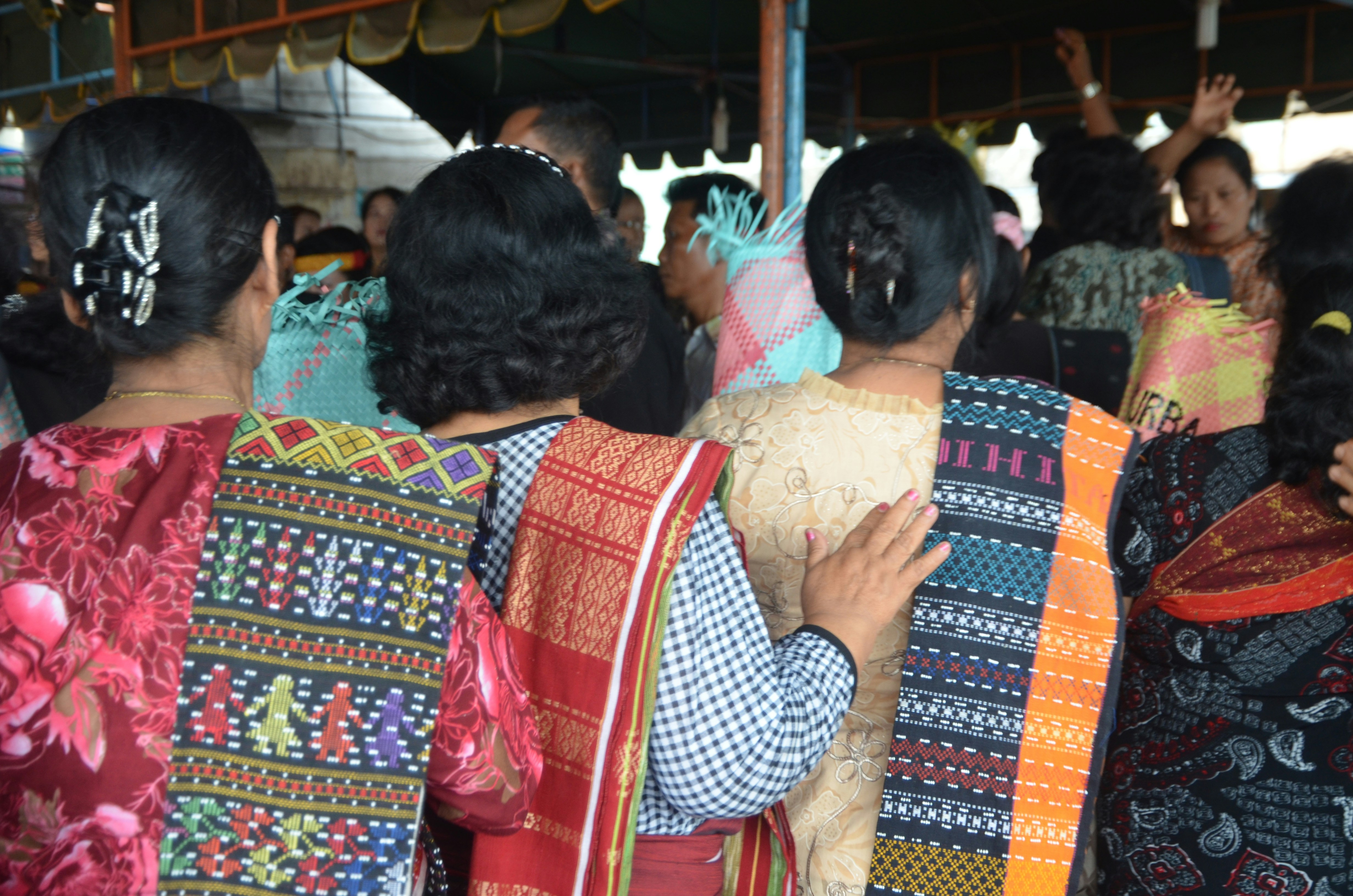 Women looking on over a funeral ritual in their local finery
