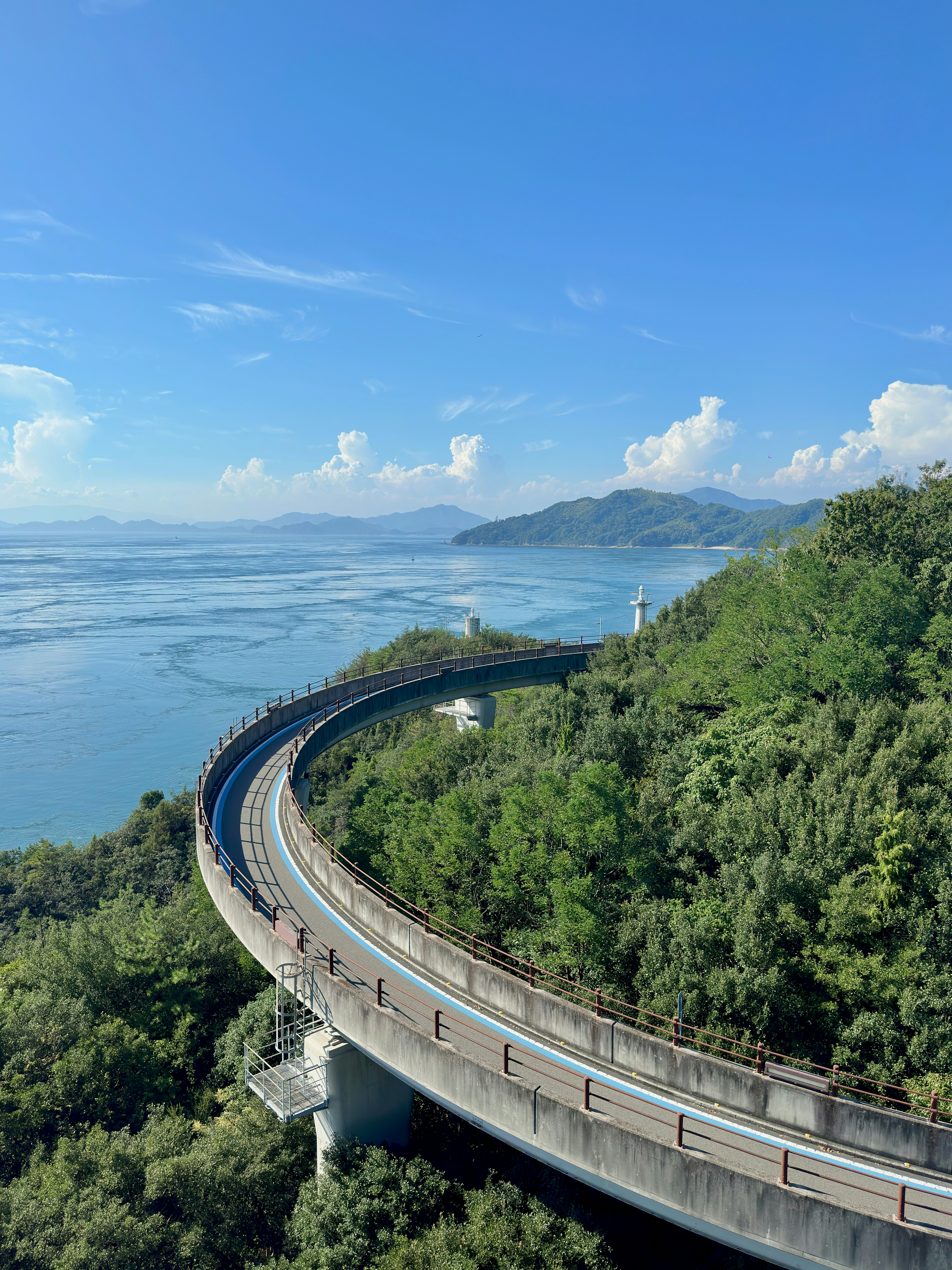 Curved road along green hills overlooking a vast blue ocean