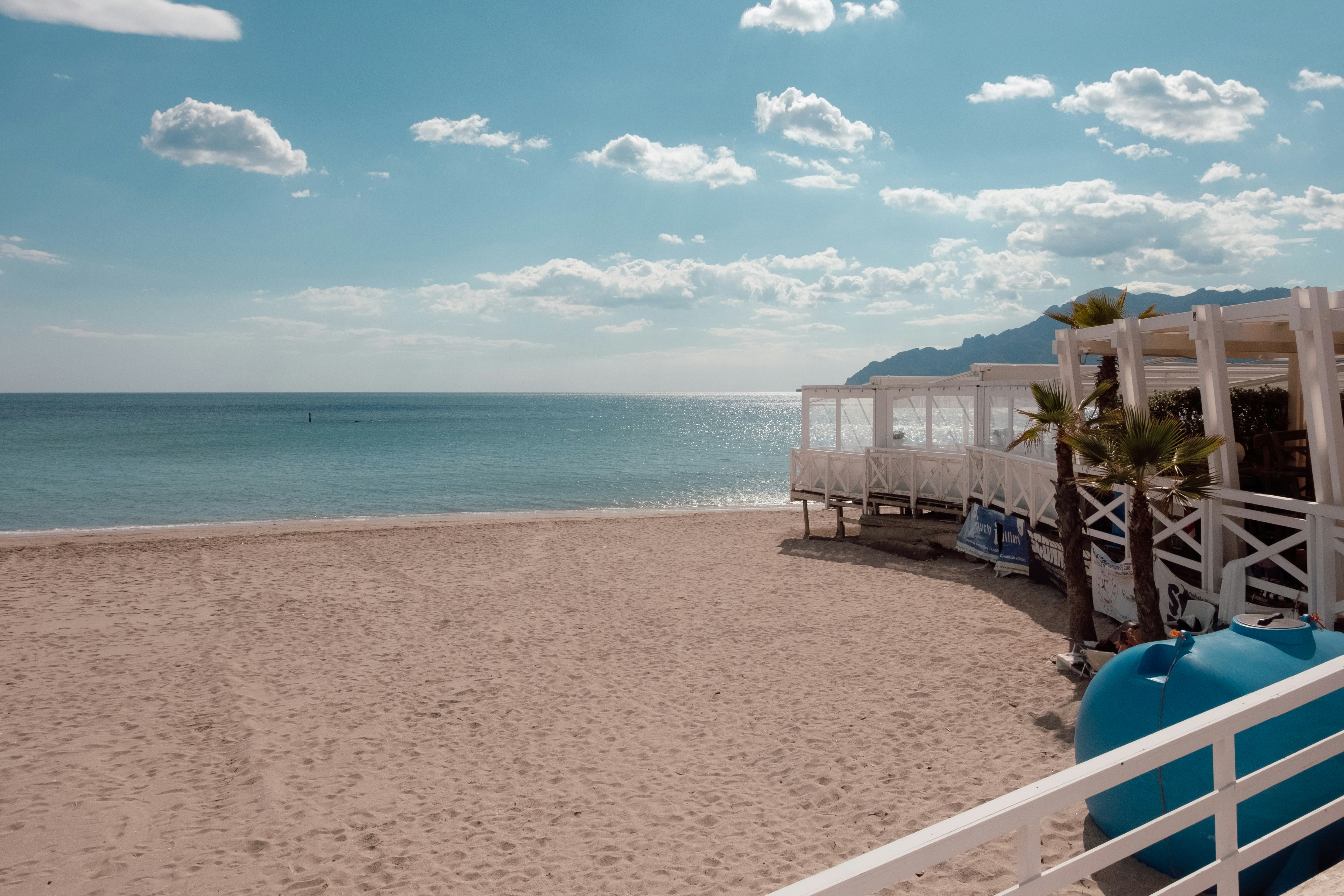 Sandy beach with white cabanas, calm ocean, and blue sky