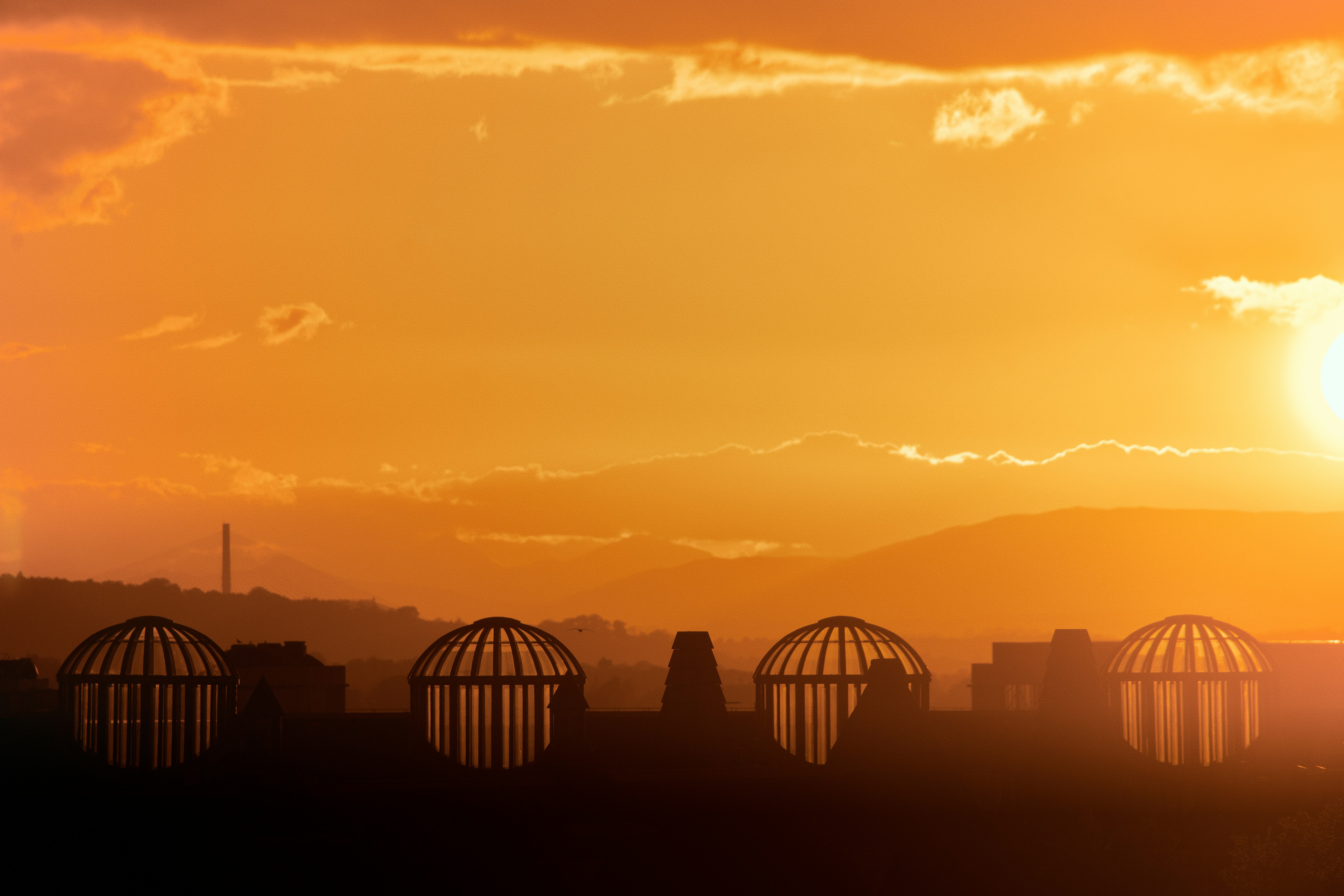 Orange sunset over a city skyline with dome structures.