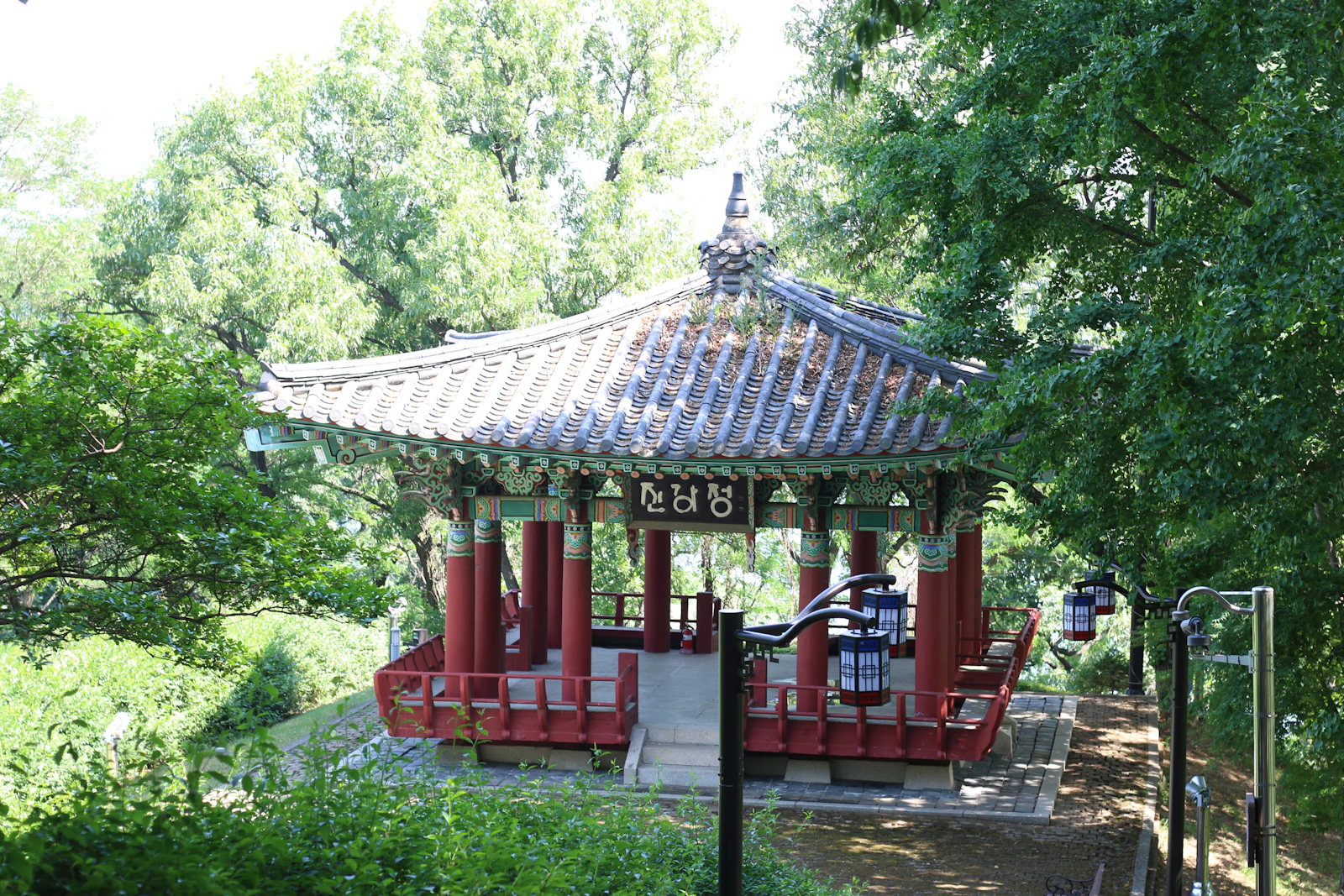 Padiglione coreano tradizionale con colonne rosse circondato da alberi verdi