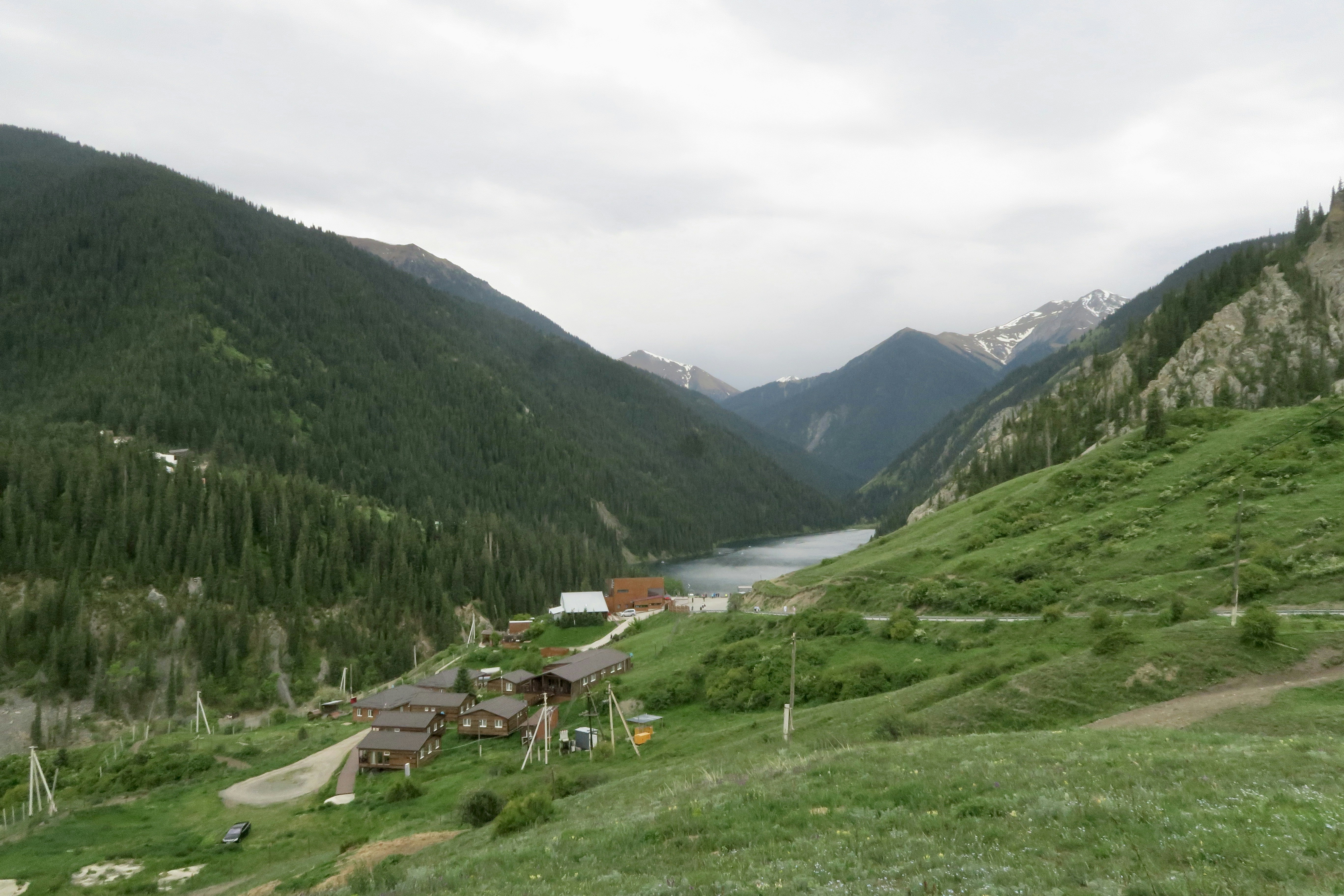Valle montuosa e rigogliosa con un lago e edifici di villaggio.