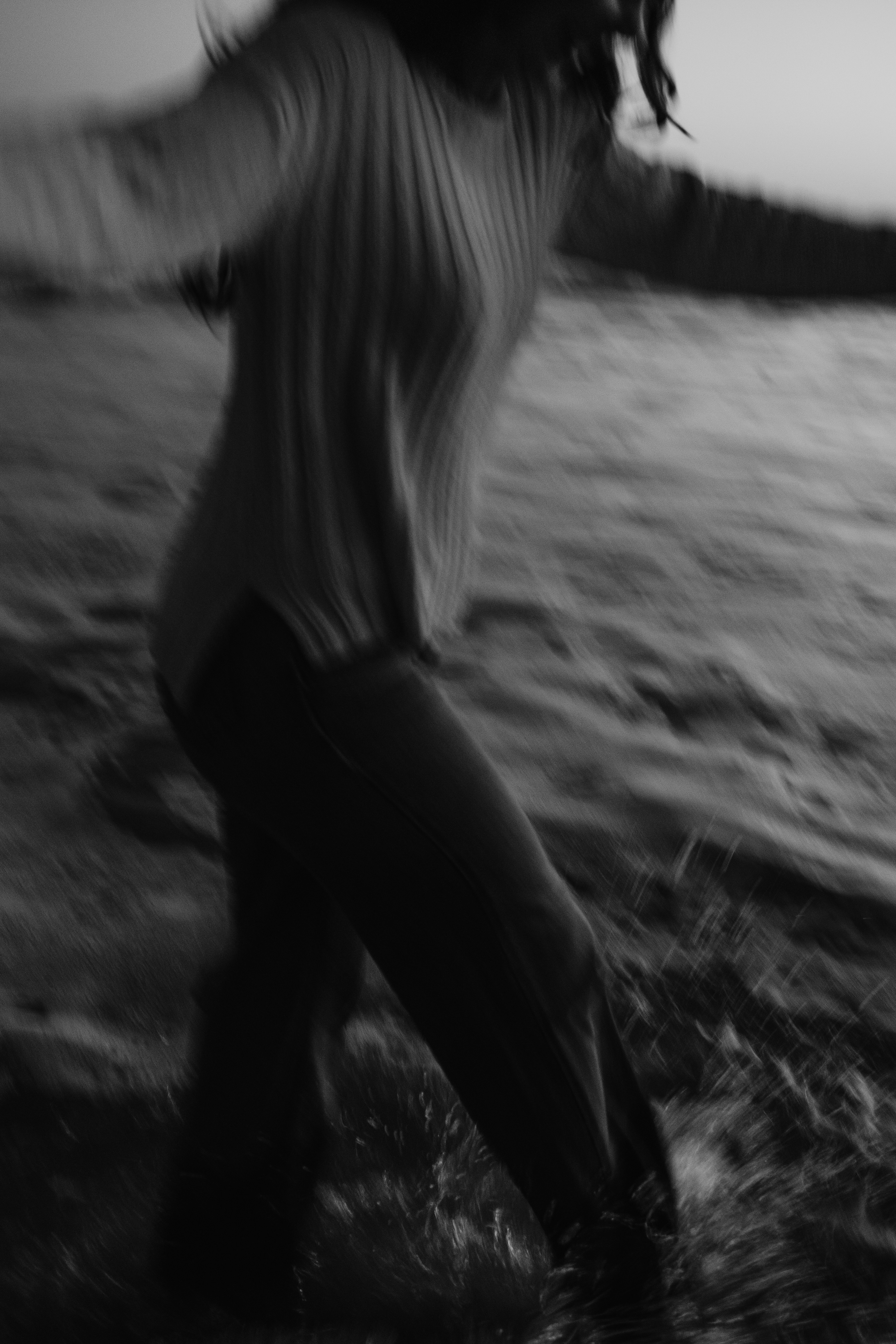 A blurred person running through water in black and white.