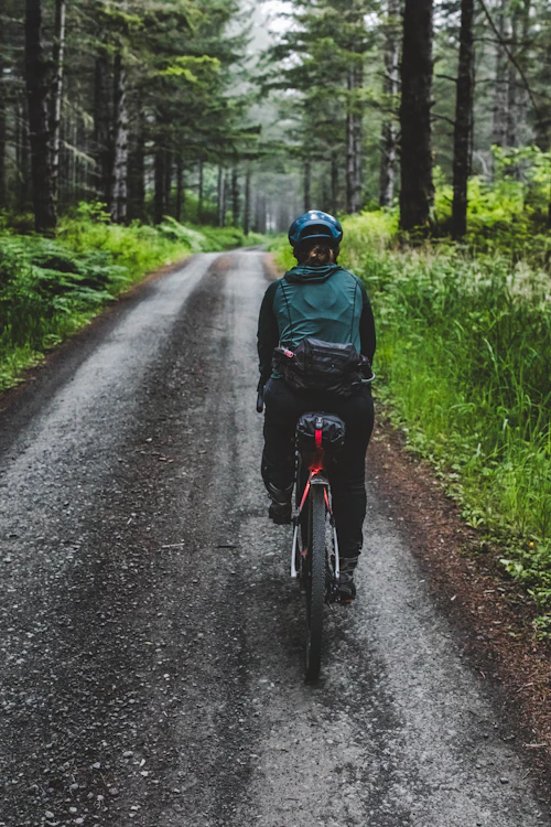 Cycliste en veste de pluie sur une route forestière mouillée