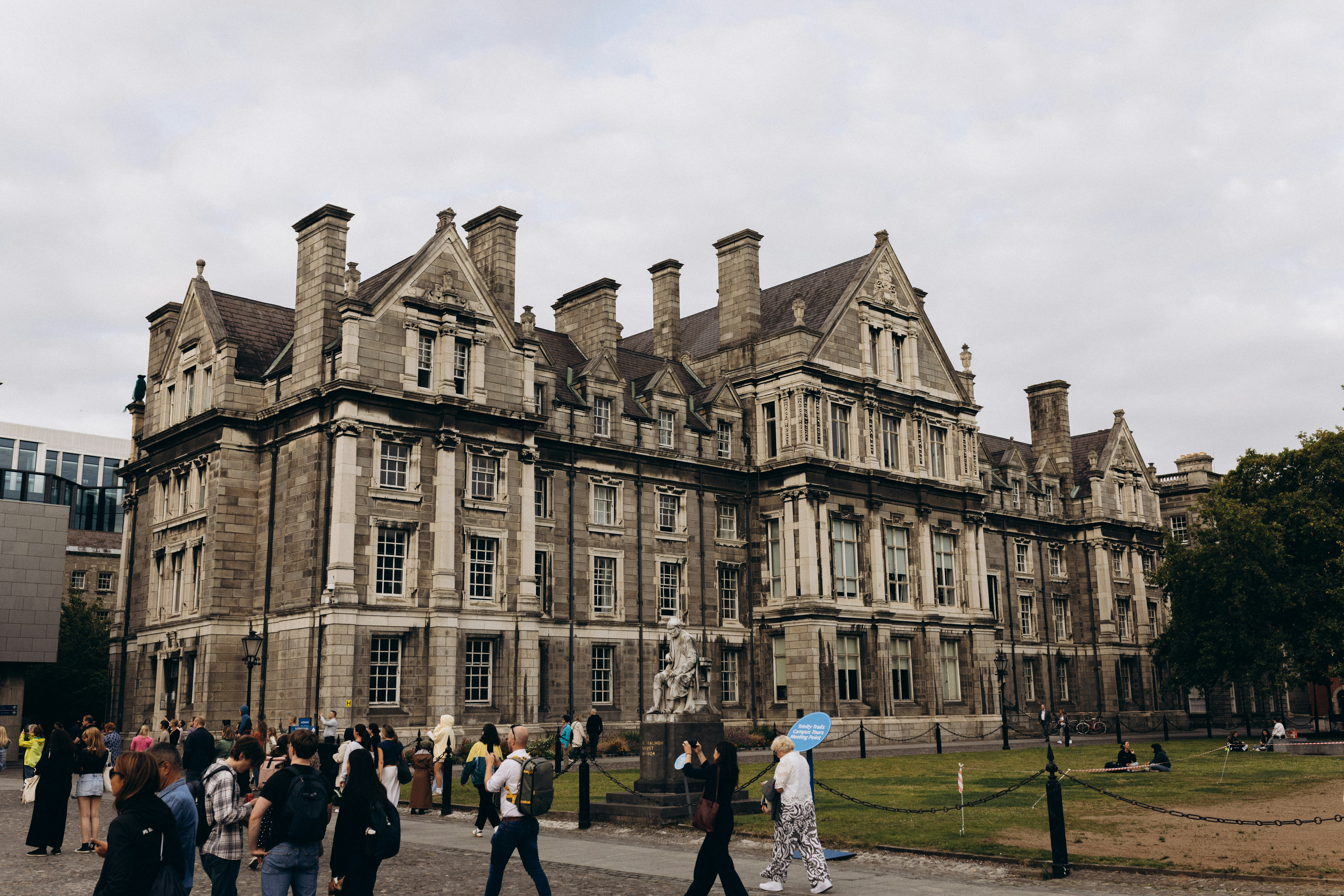 Historic stone building with people walking on a cloudy day.