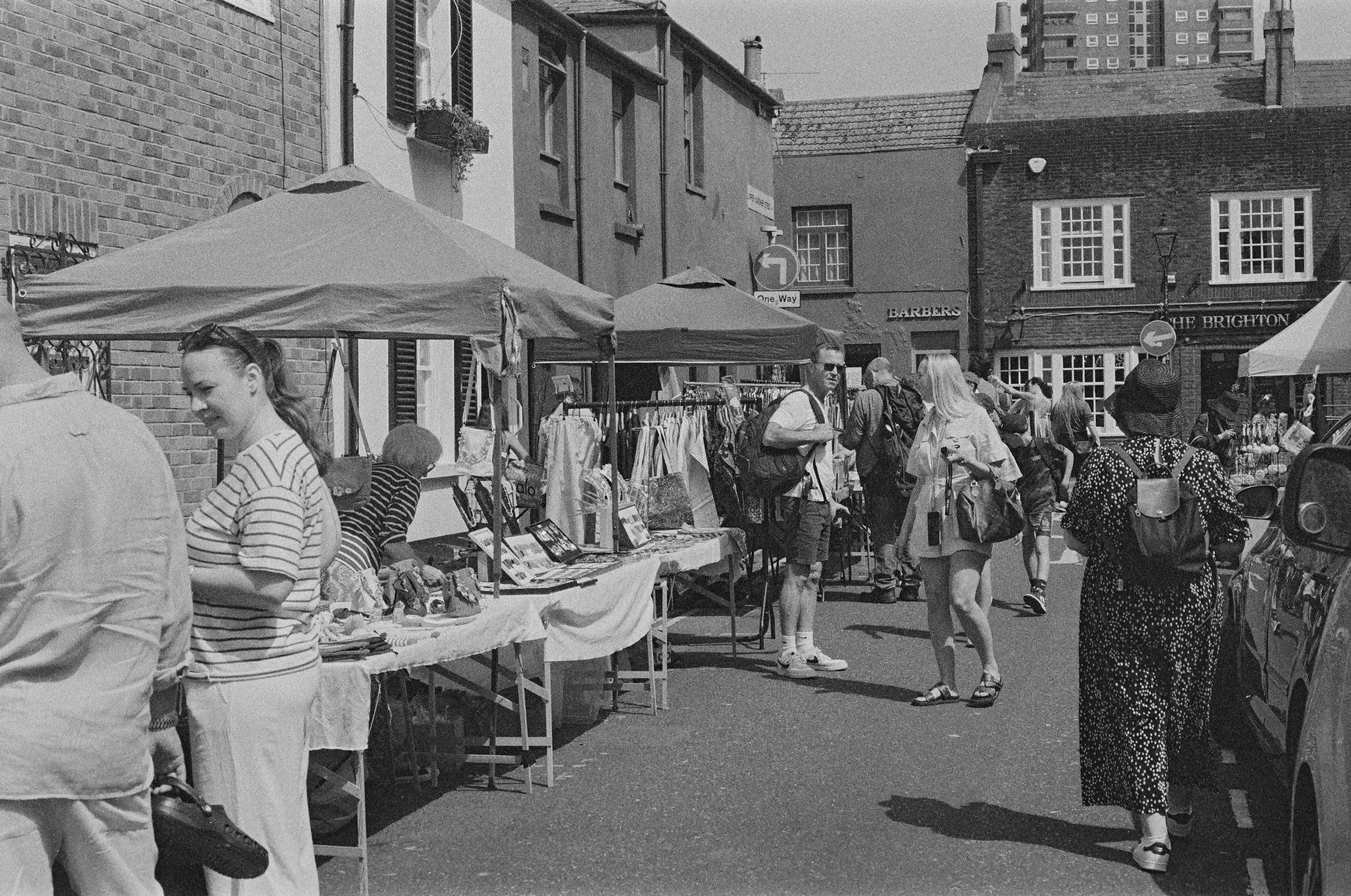Outdoor market scene with people browsing stalls.