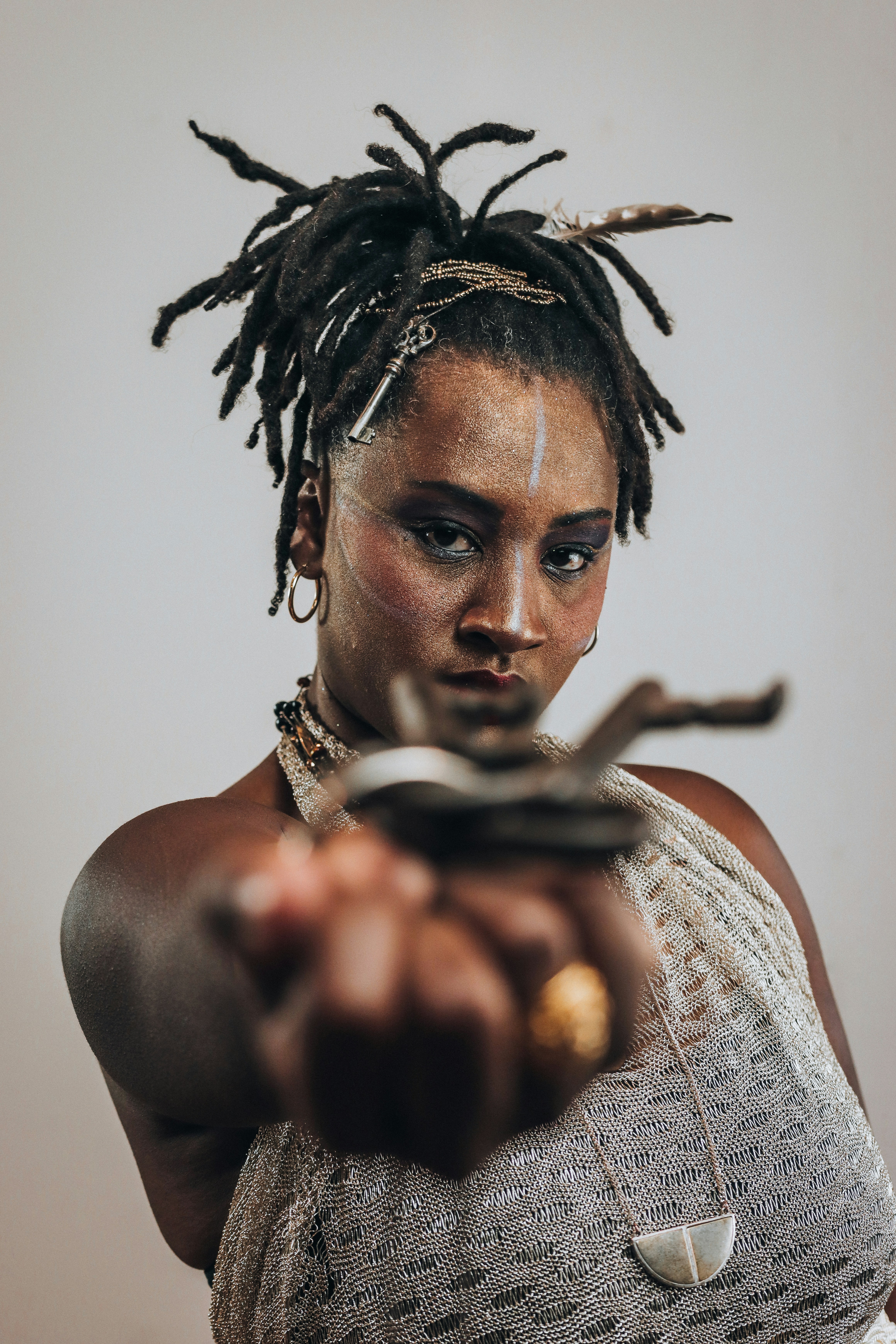 Woman with dreadlocks and face paint extends a metallic key.