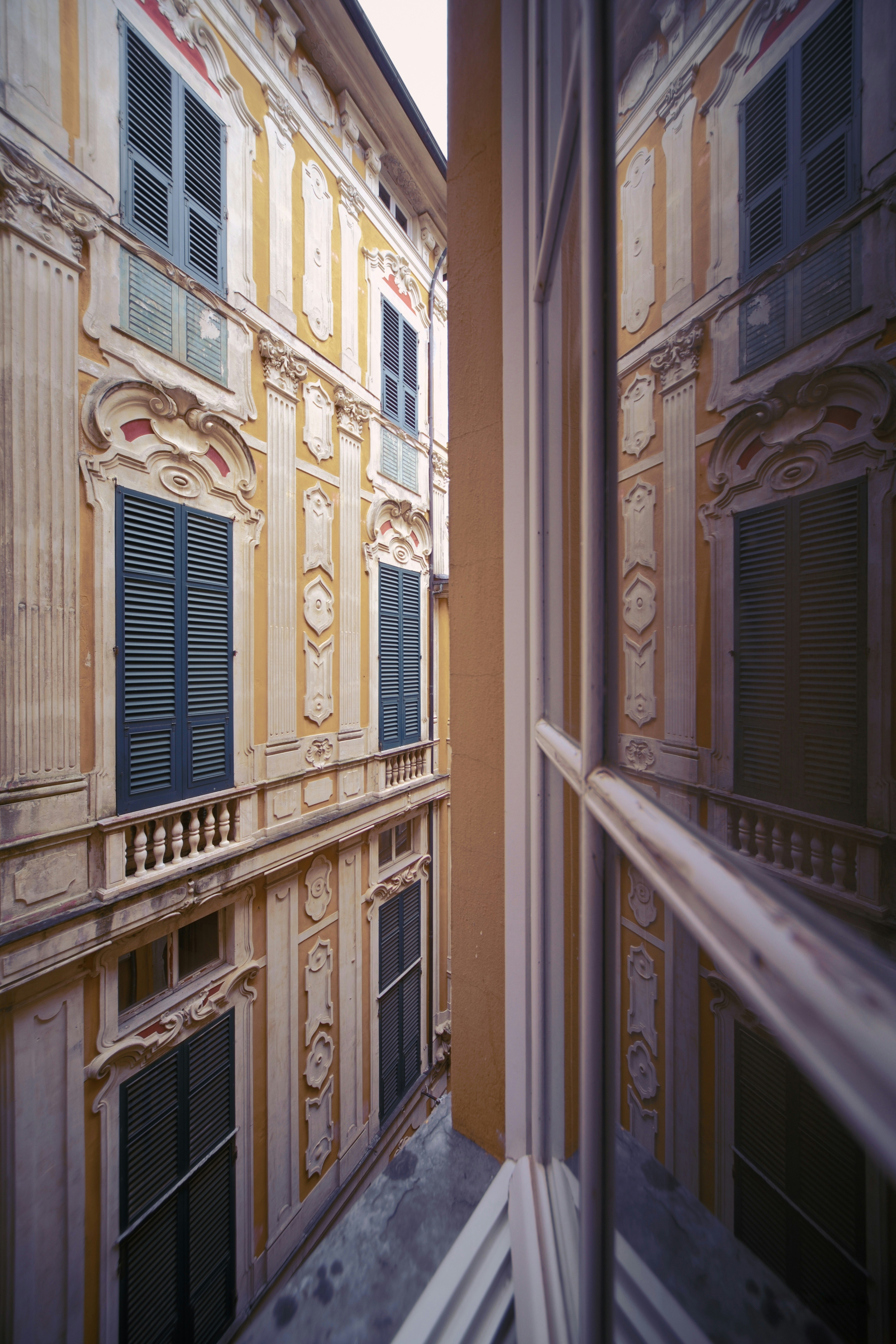 Narrow alley between ornate buildings with window reflection.