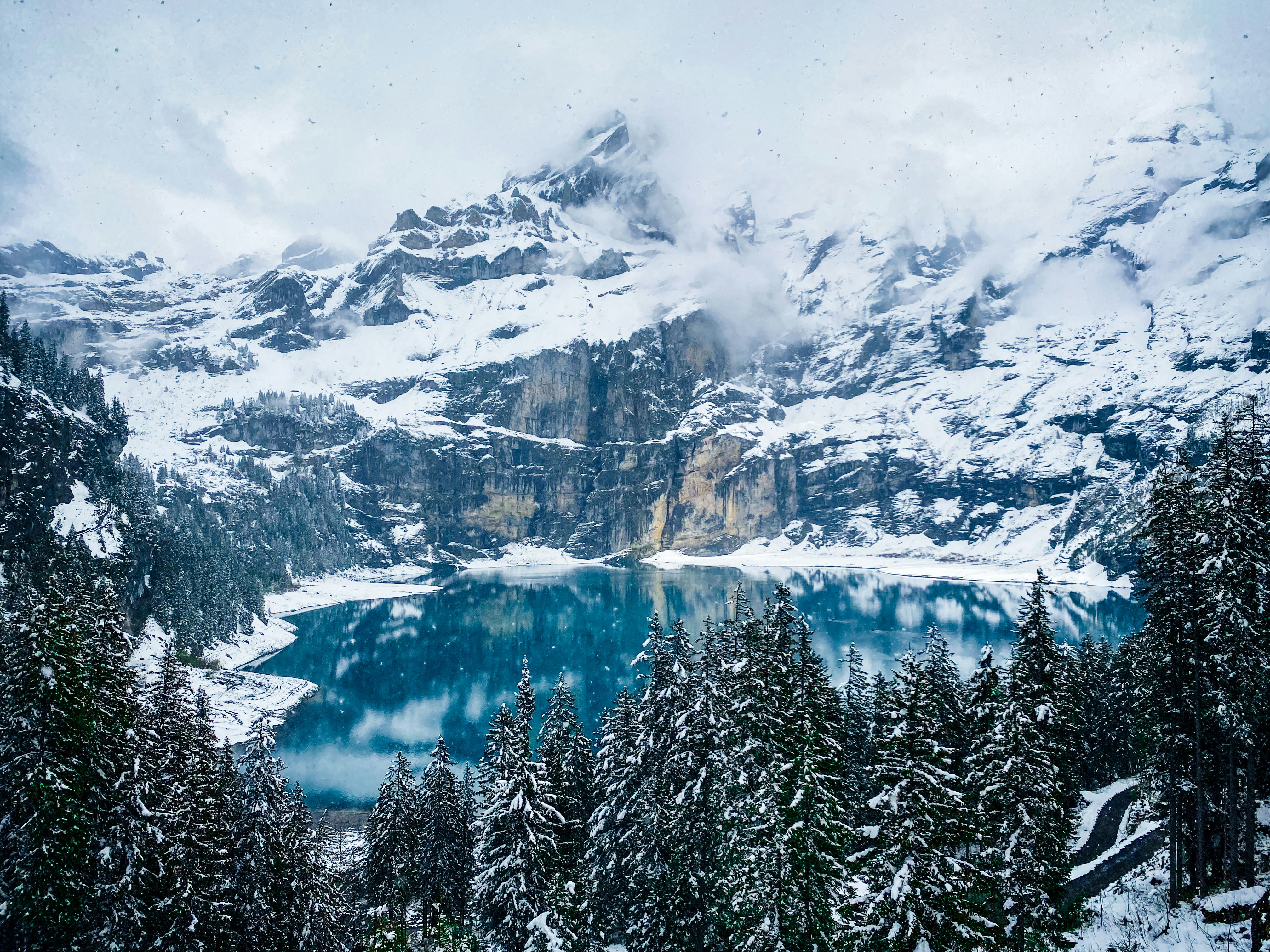 Montanhas nevadas emolduram um lago azul imaculado e pinheiros
