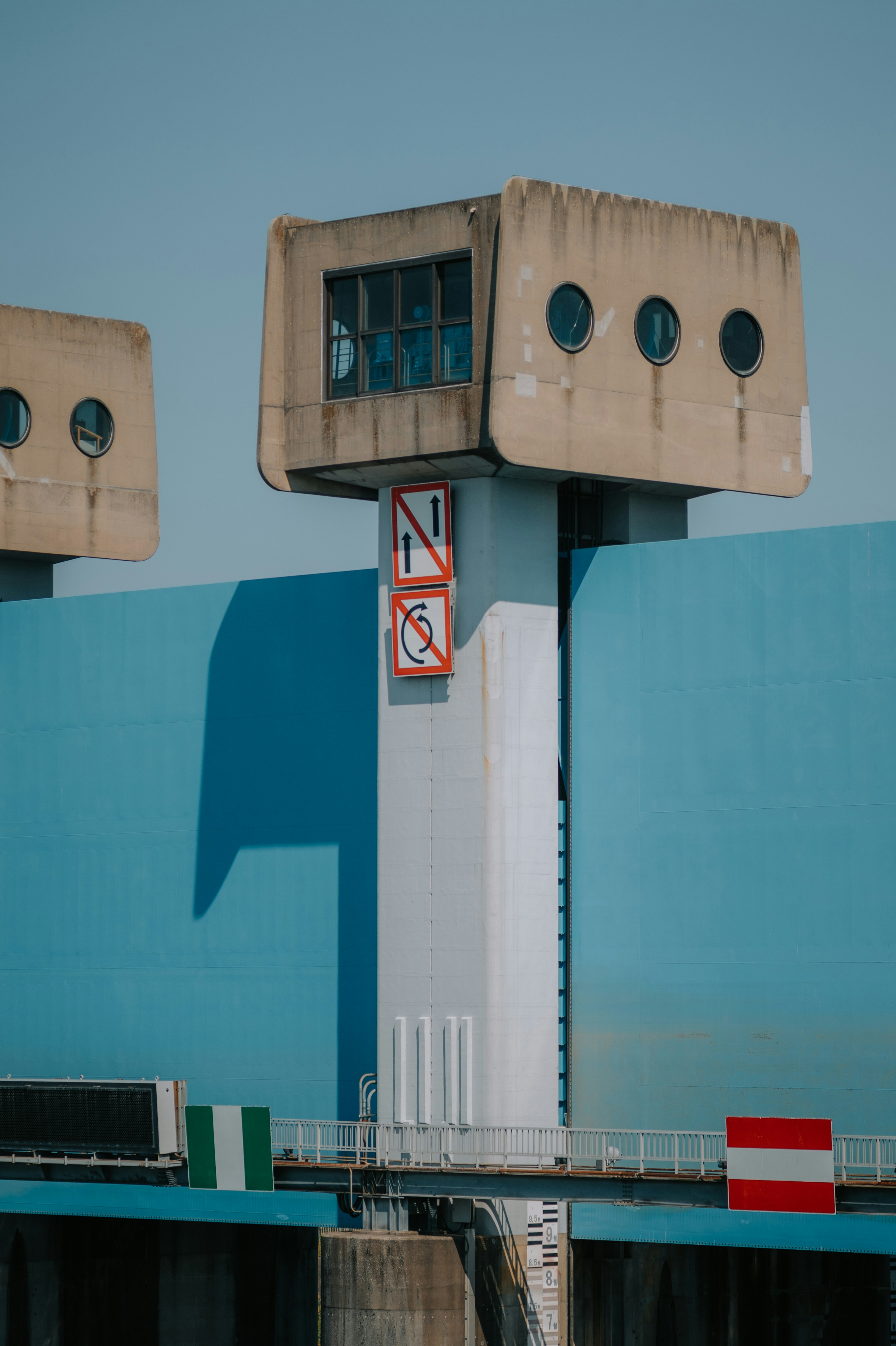 Modern concrete control tower overlooks a large blue dam.