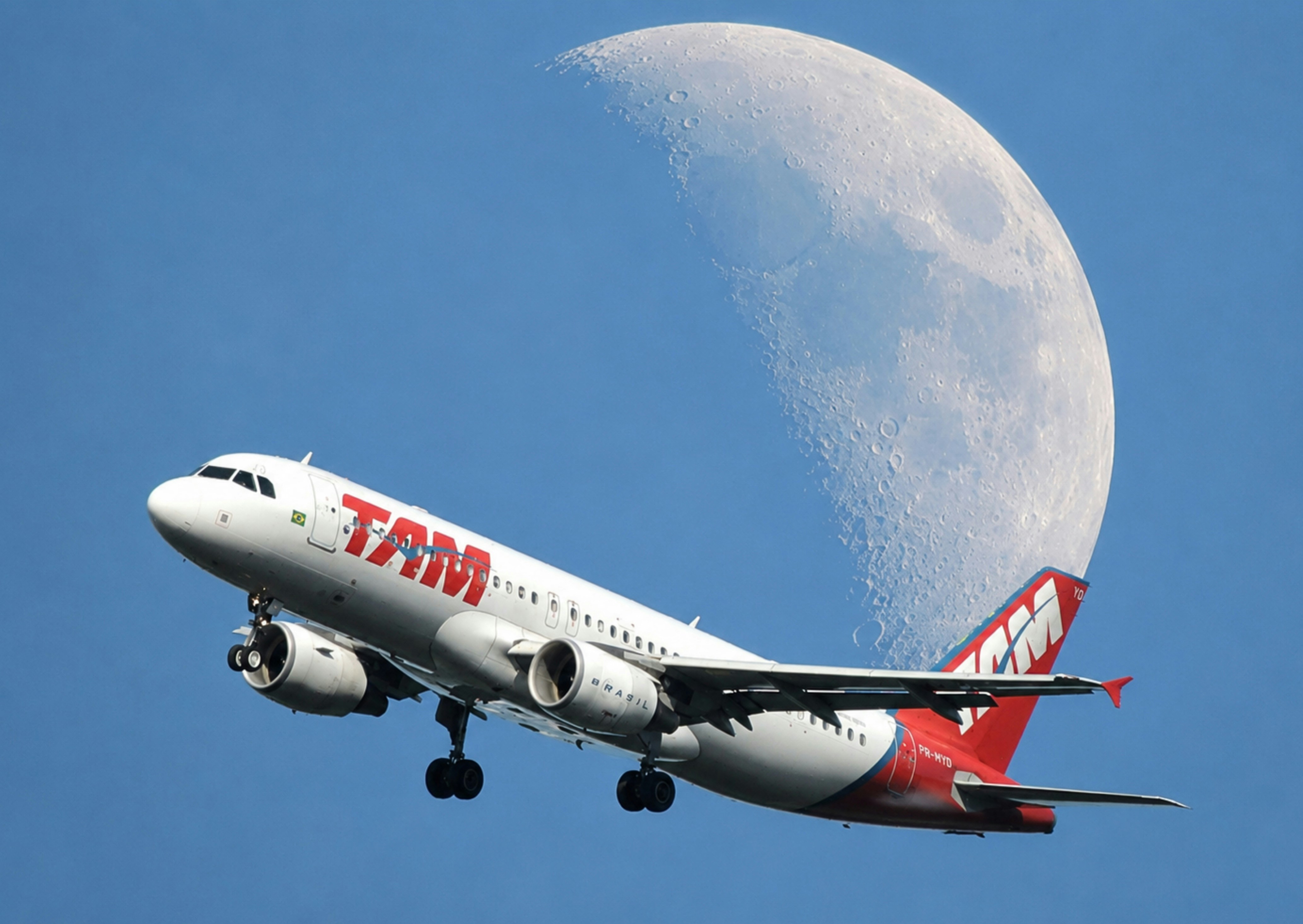 Tam airplane flying in blue sky with a crescent moon.