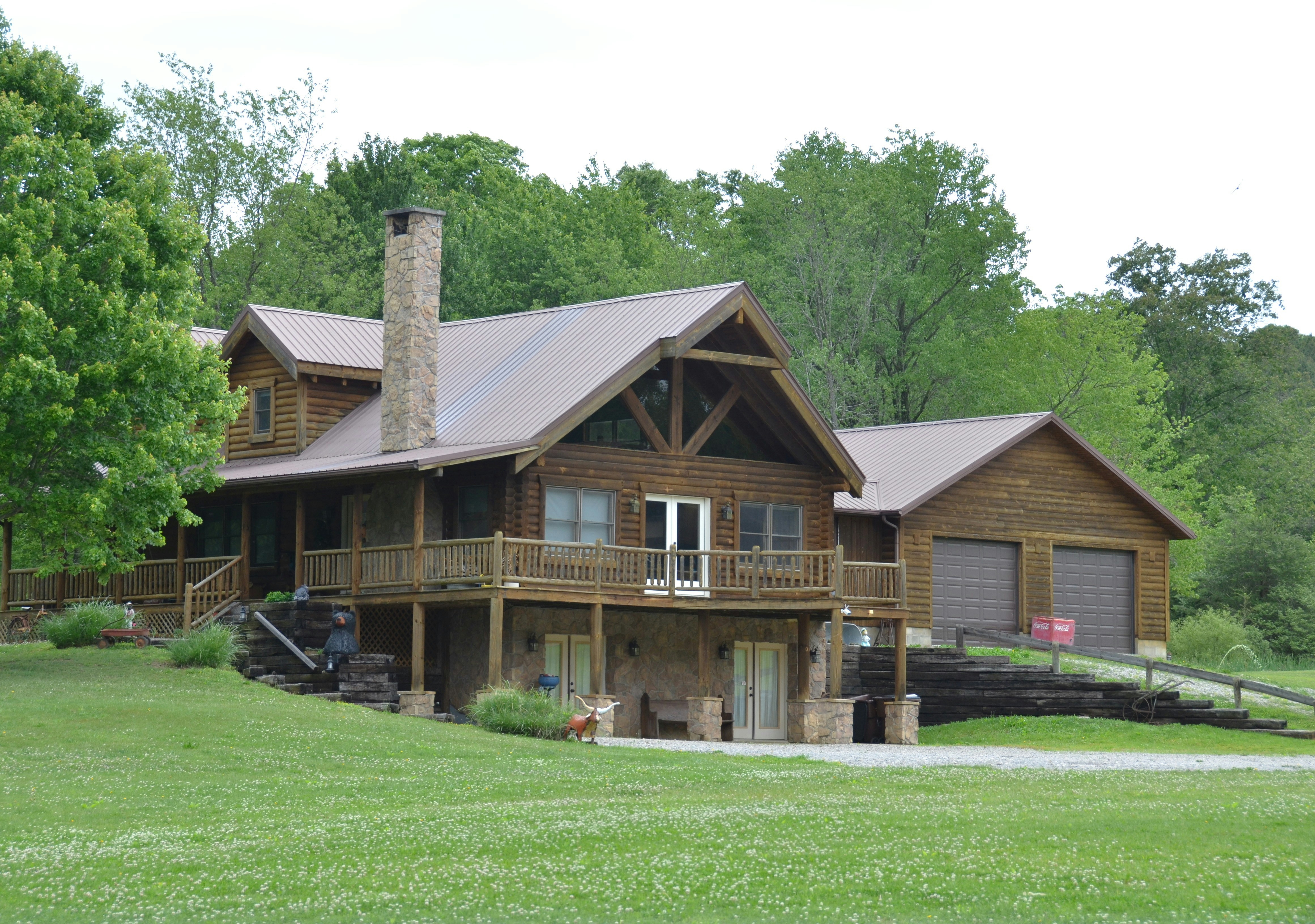 Rustic wooden cabin house with a garage and green lawn.