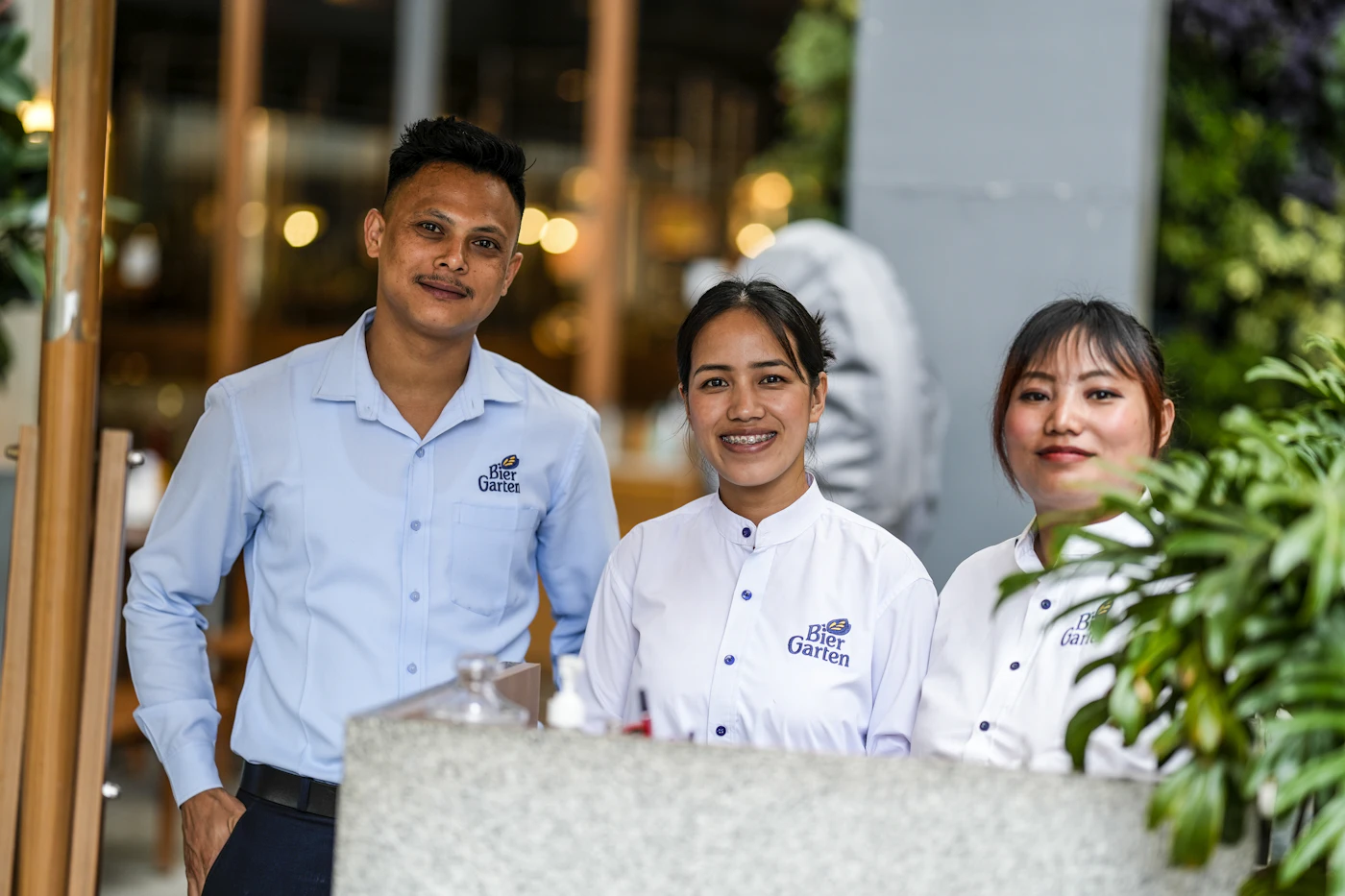 Three smiling restaurant staff behind the counter