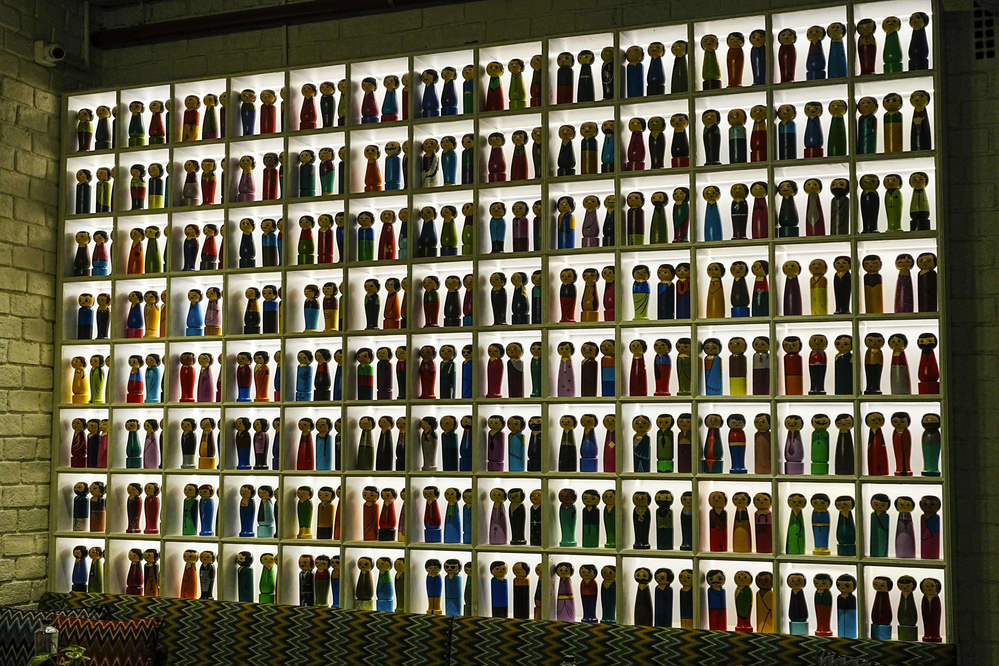 Illuminated wall display featuring numerous colorful bottles.