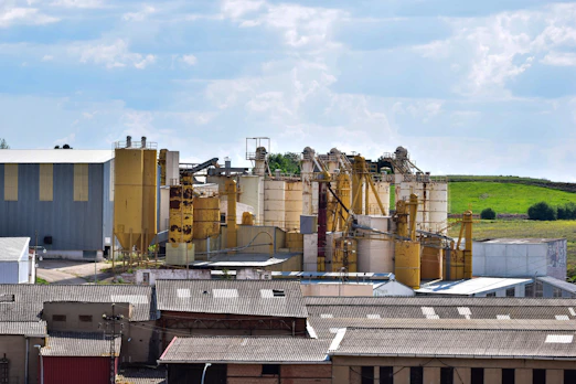 Industrial complex with silos and buildings under a blue sky.