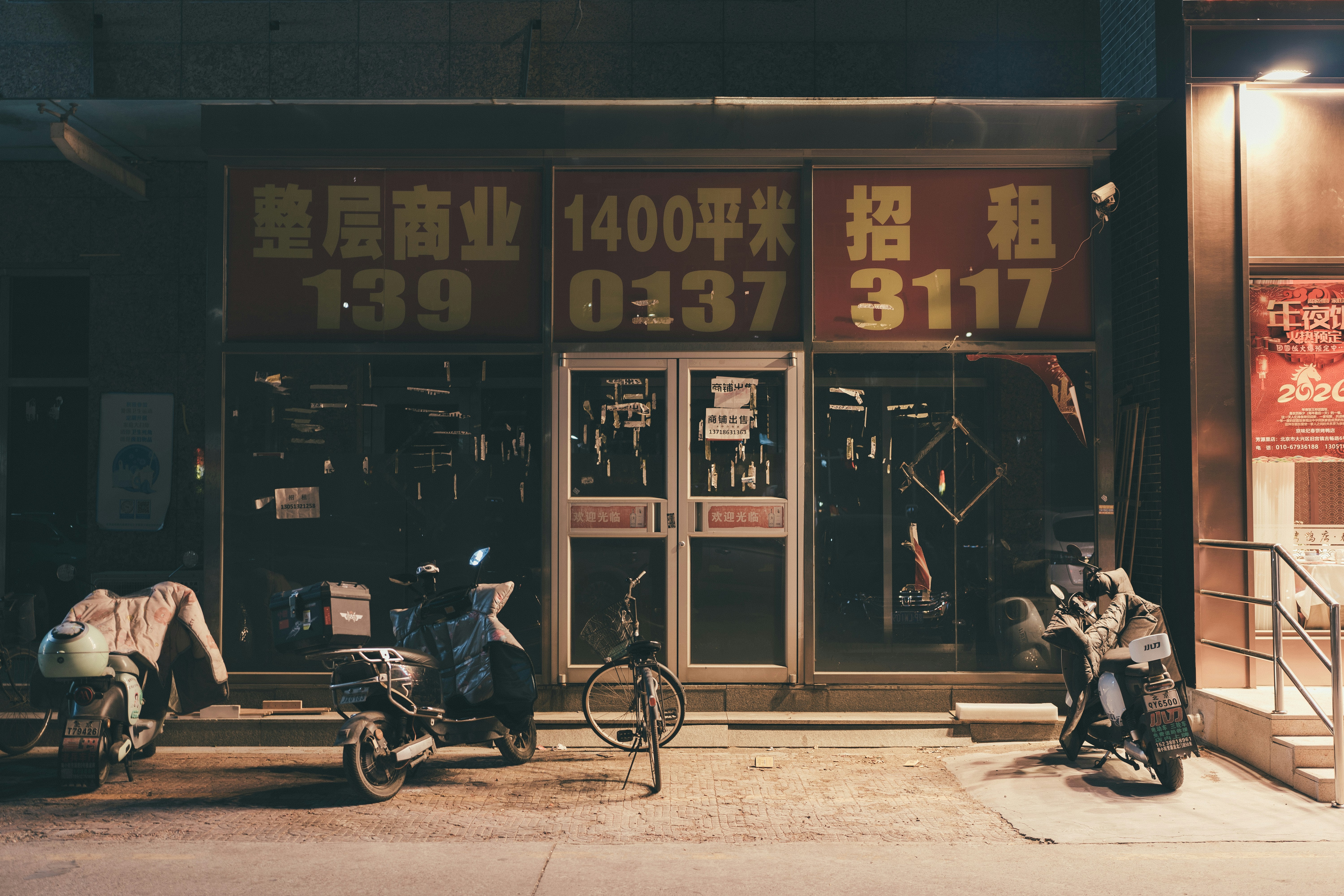 Storefront with red signs and parked motorcycles at night.