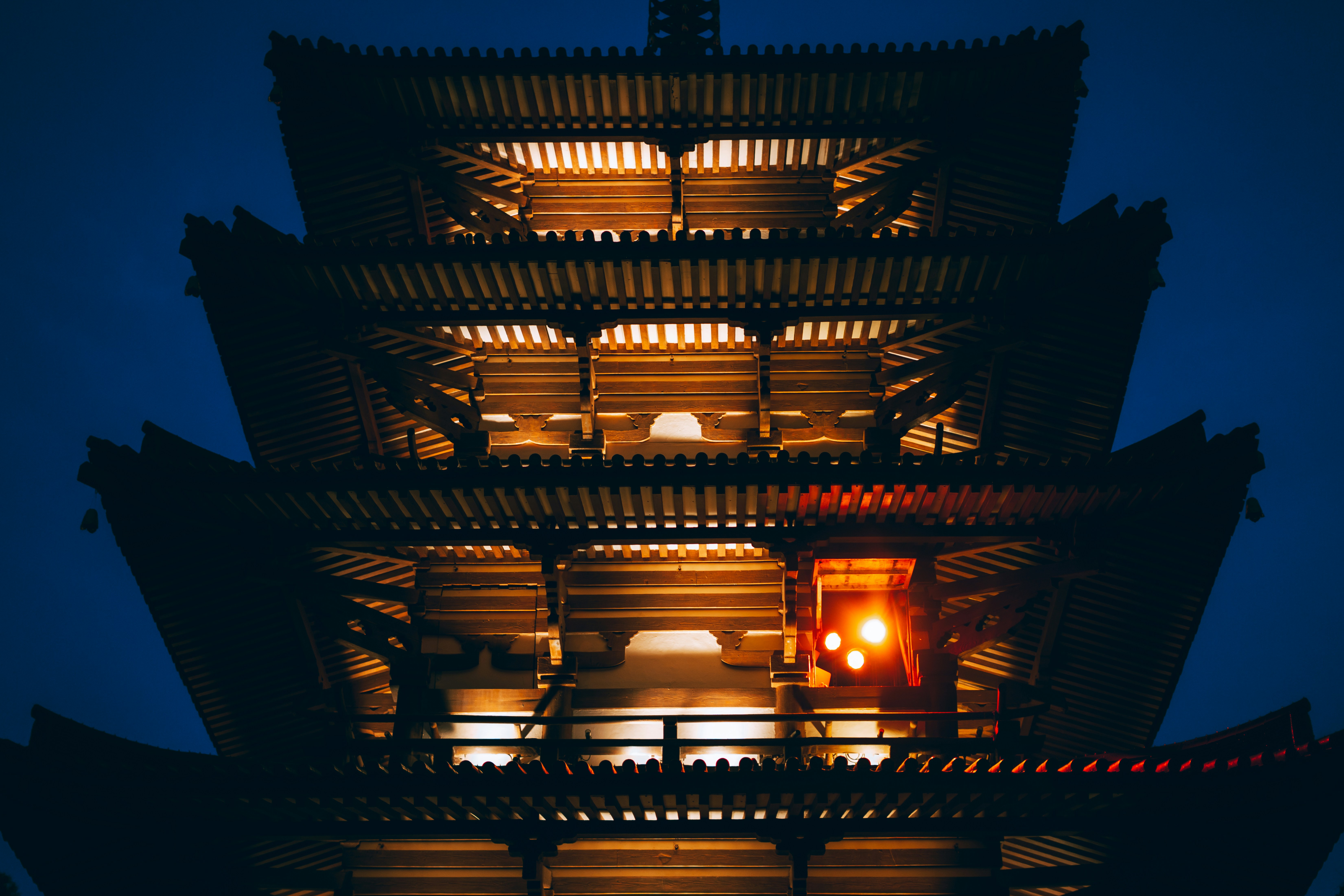 Pagoda tradisional yang diterangi di malam hari dengan lampu hangat.