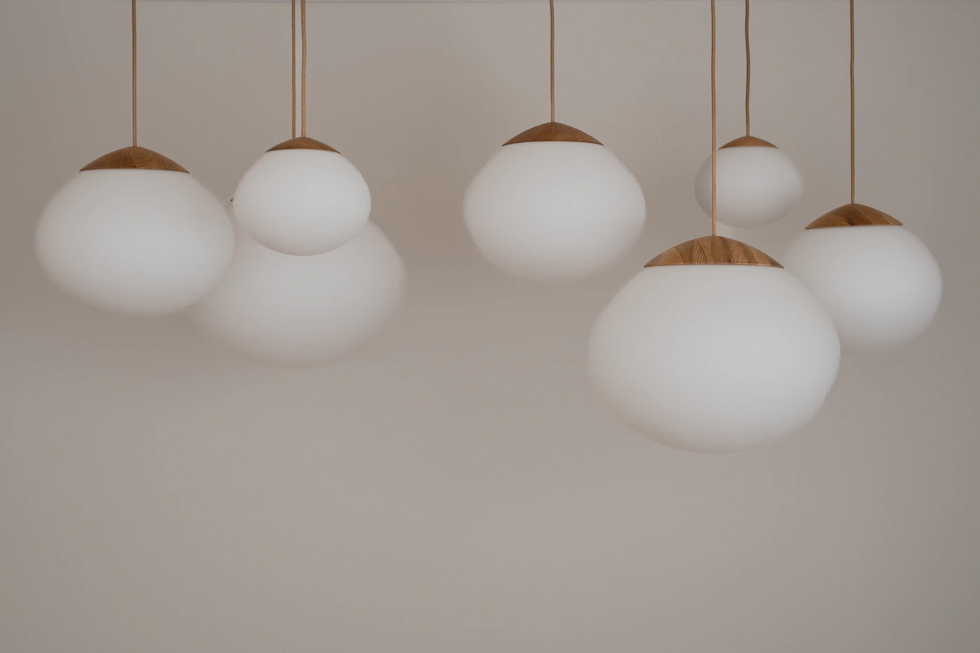 Cluster of white globe pendant lights with pale wooden caps