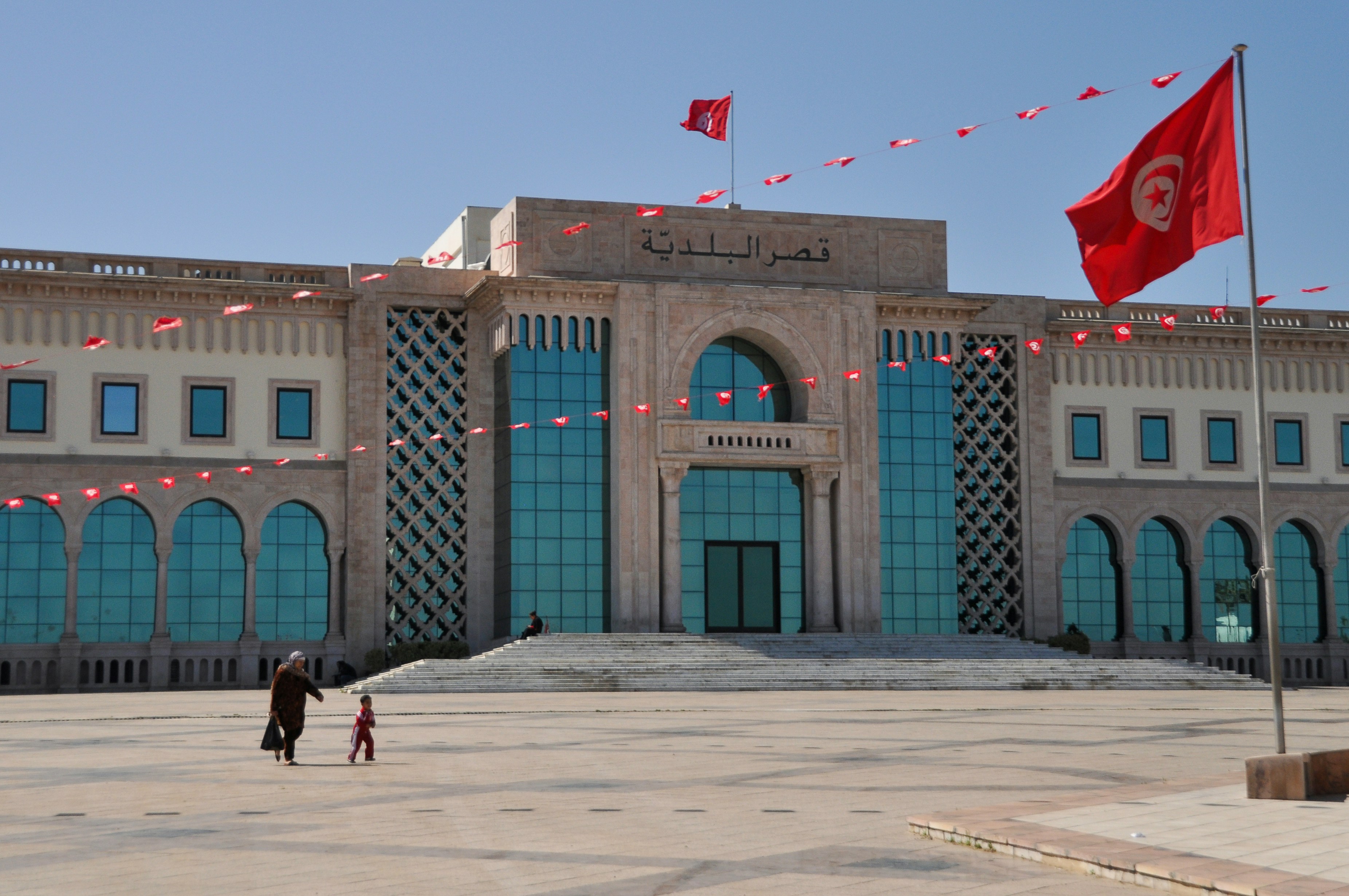 Grand tunisian building with national flags under a clear sky.