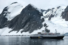 Cruise ship sailing past snow-capped mountains and glacier scenery