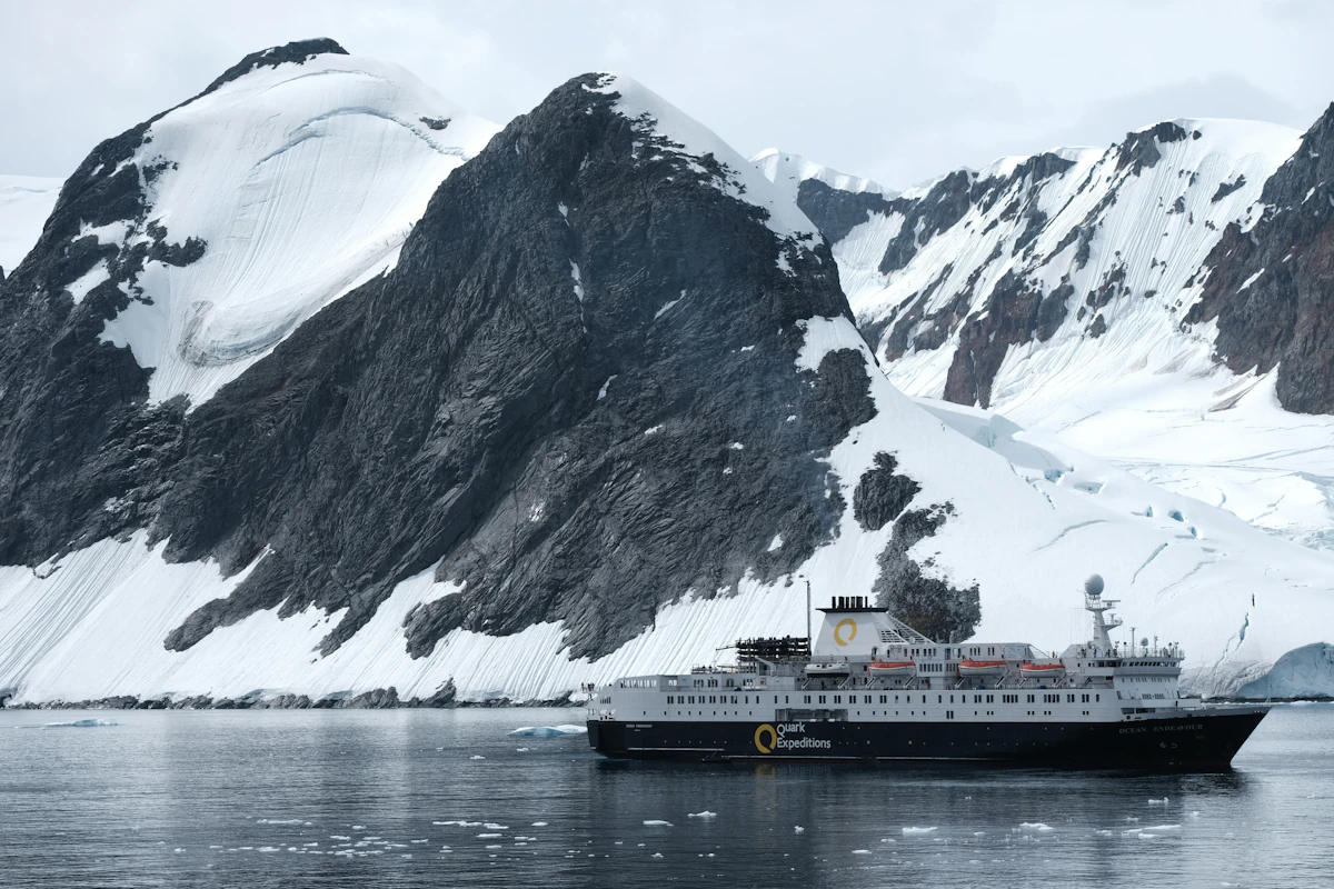 Cruise ship sailing past snow-capped mountains and glacier scenery